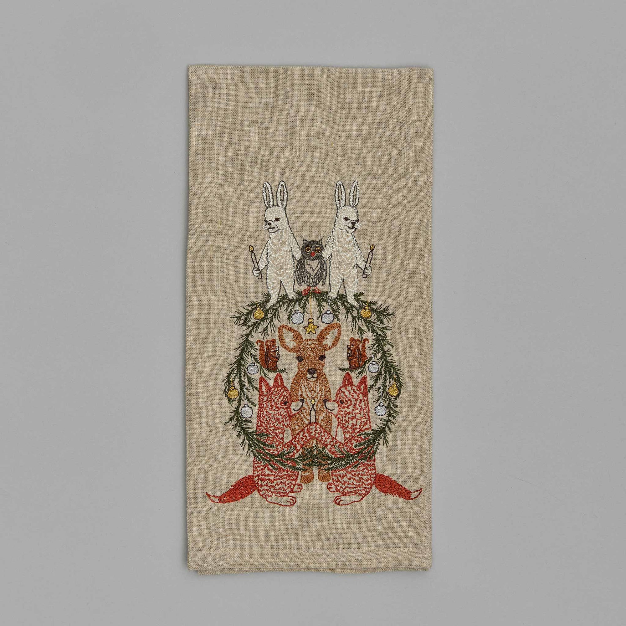 Decorative towel with embroidered design of animals and a wreath on a beige background