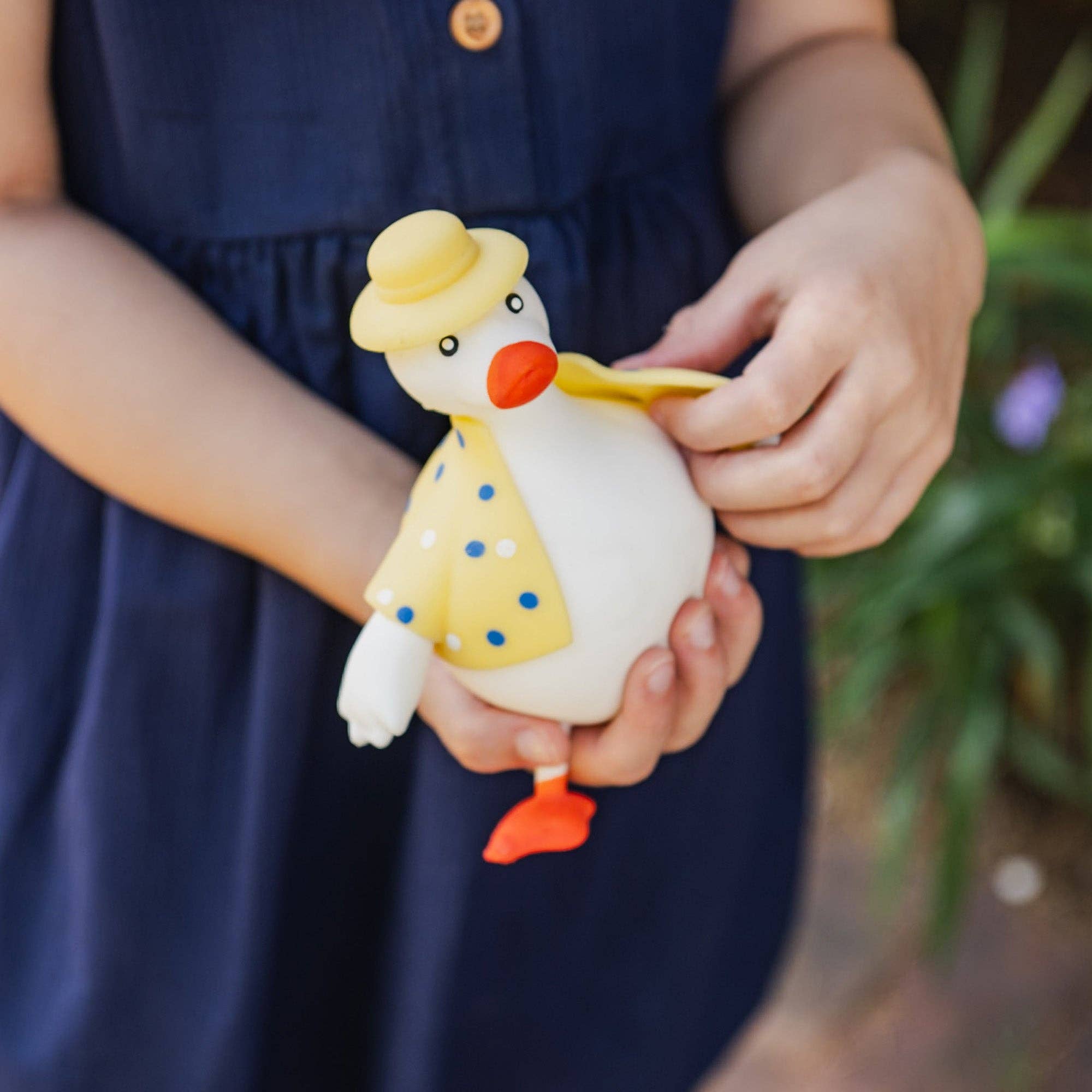Child holding a toy duck with a yellow hat and orange beak