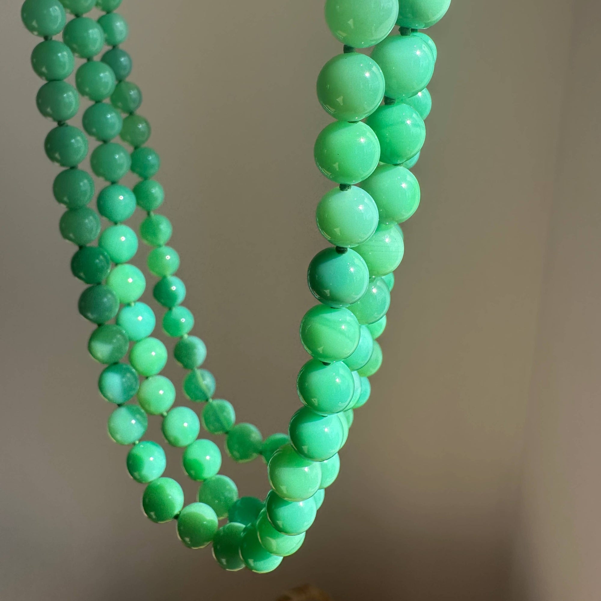 Green beaded necklace on a plain background