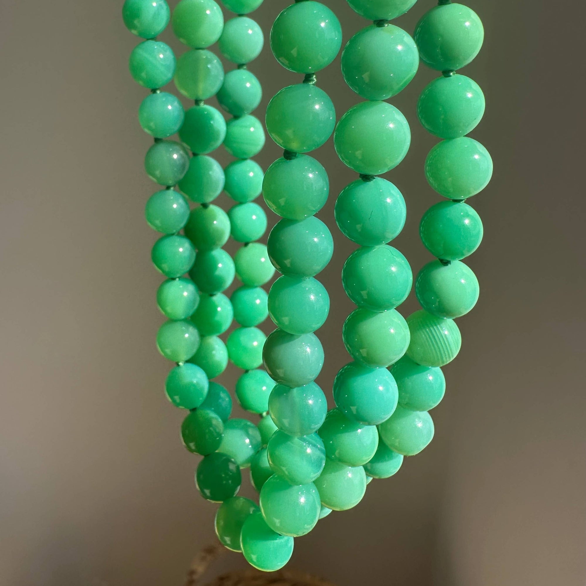 Green beaded necklace on a neutral background