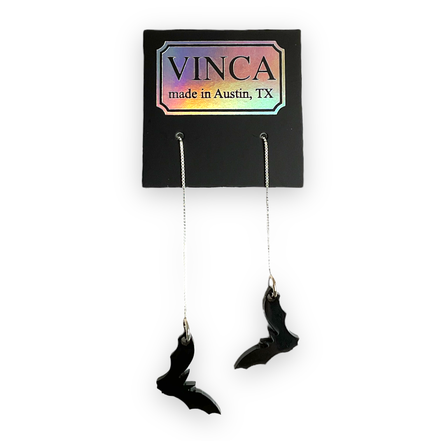 Black wing-shaped earrings on a Vinca branded card with a white background