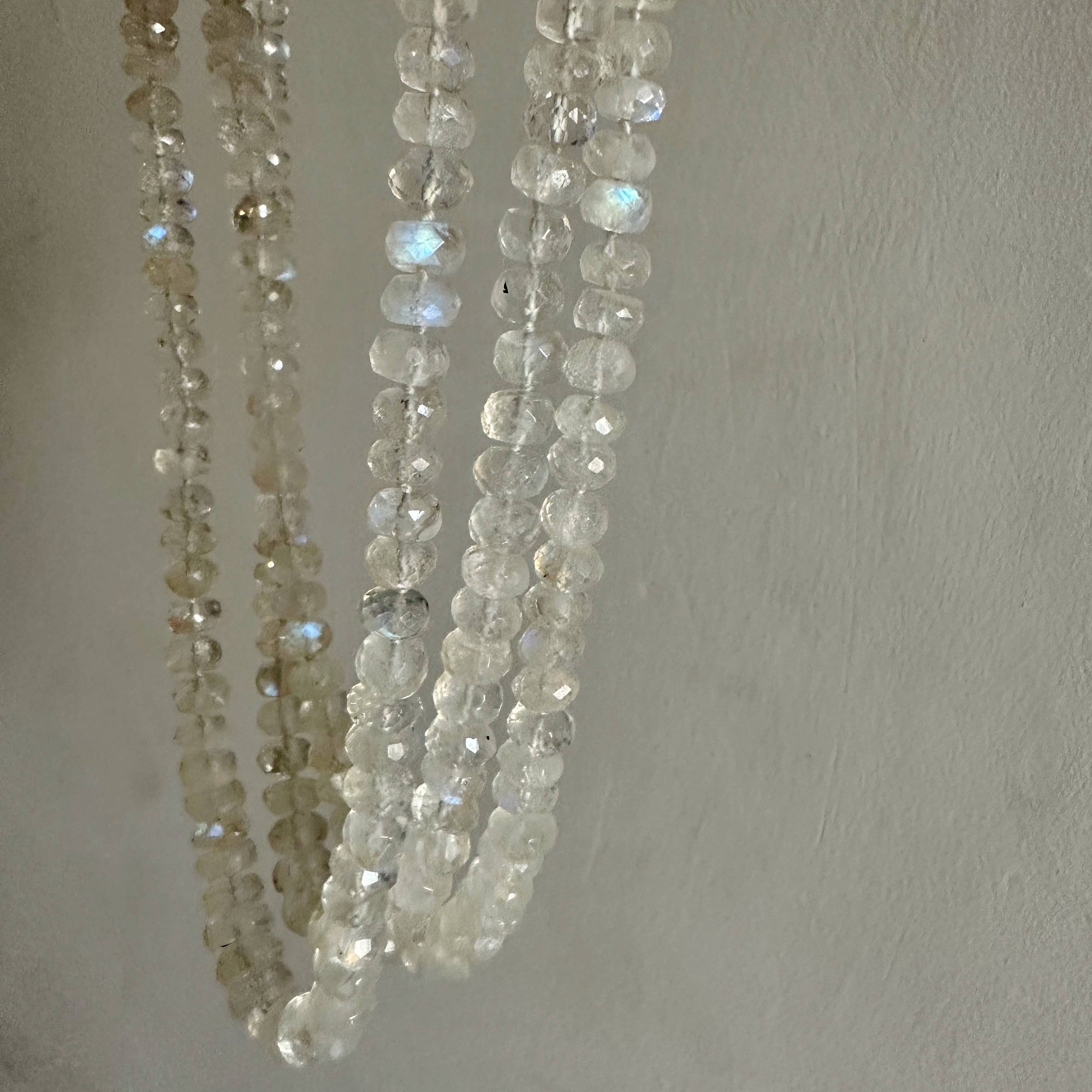 Three strands of clear beads on a light gray background