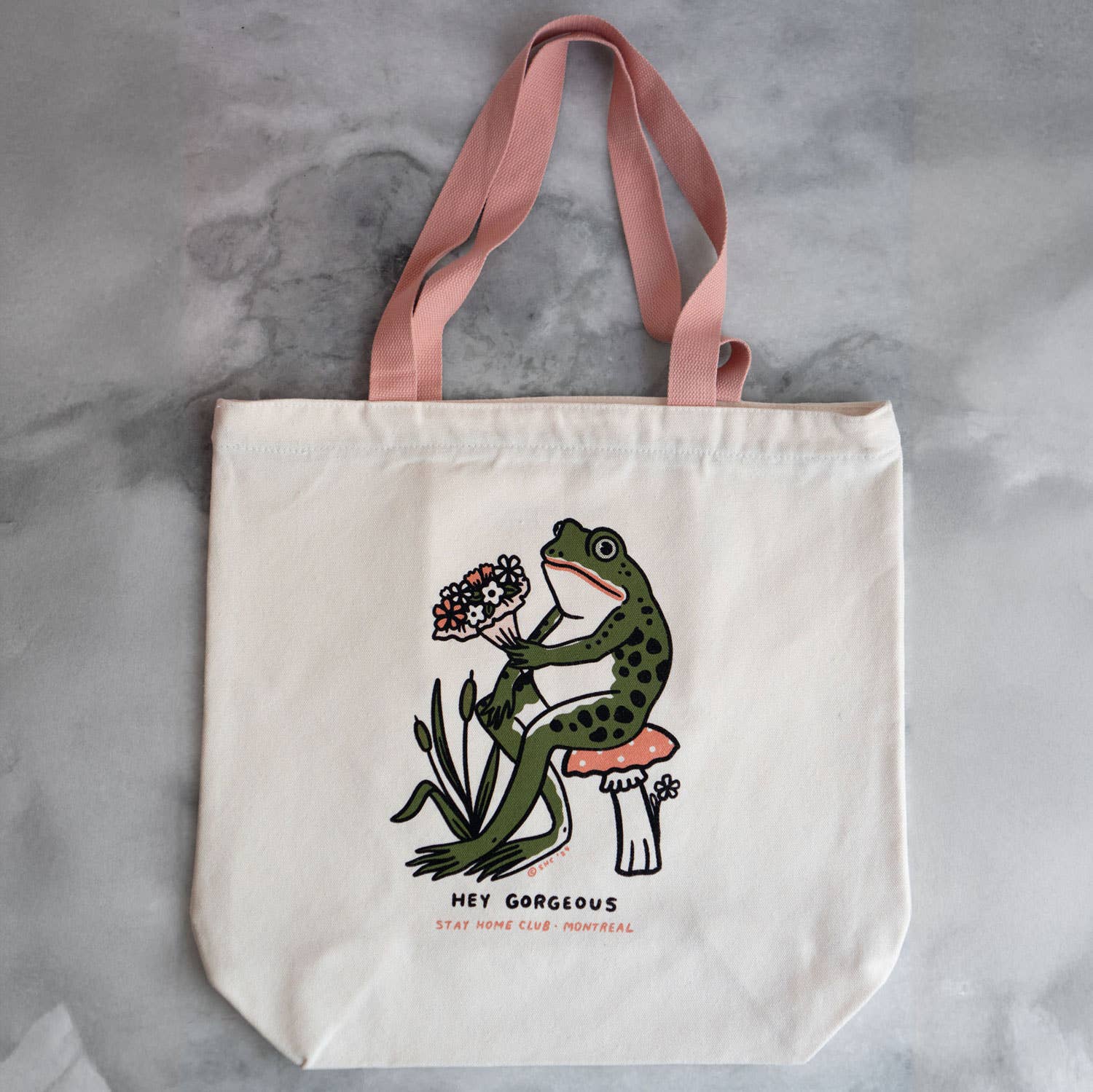 Tote bag with a frog design and 'Hey Gorgeous' text on a gray background