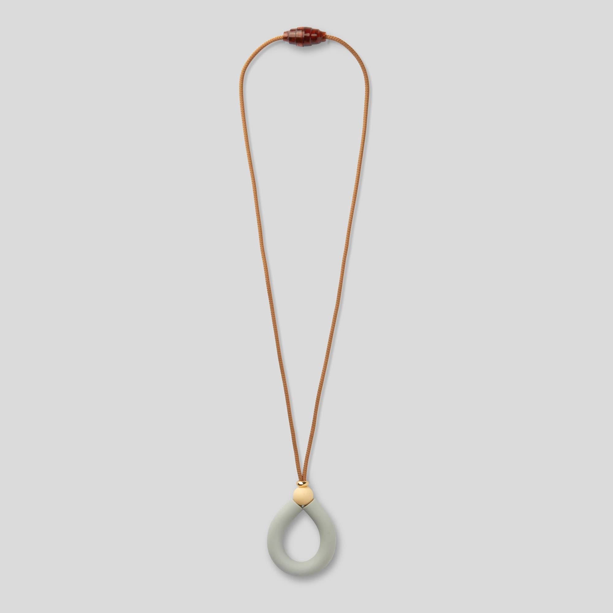 Necklace with a long brown cord and a green teardrop pendant on a light gray background