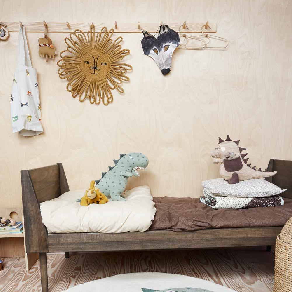 Children's bedroom with wooden bed, dinosaur-themed rug, and wall decorations.