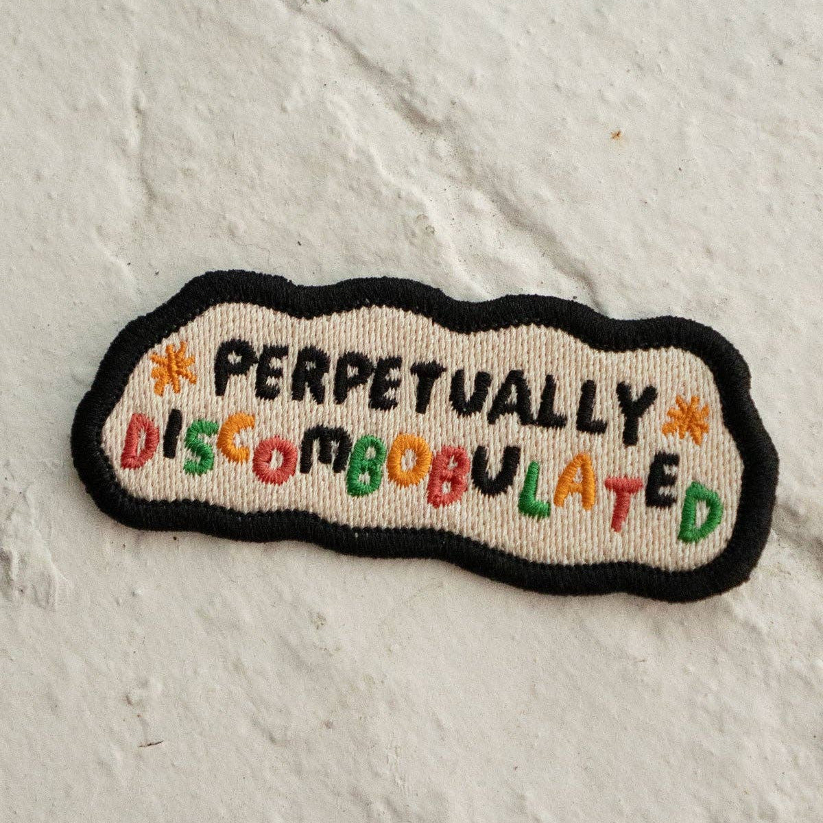 Embroidered patch with 'Perpetually Discombobulated' text on a textured white background