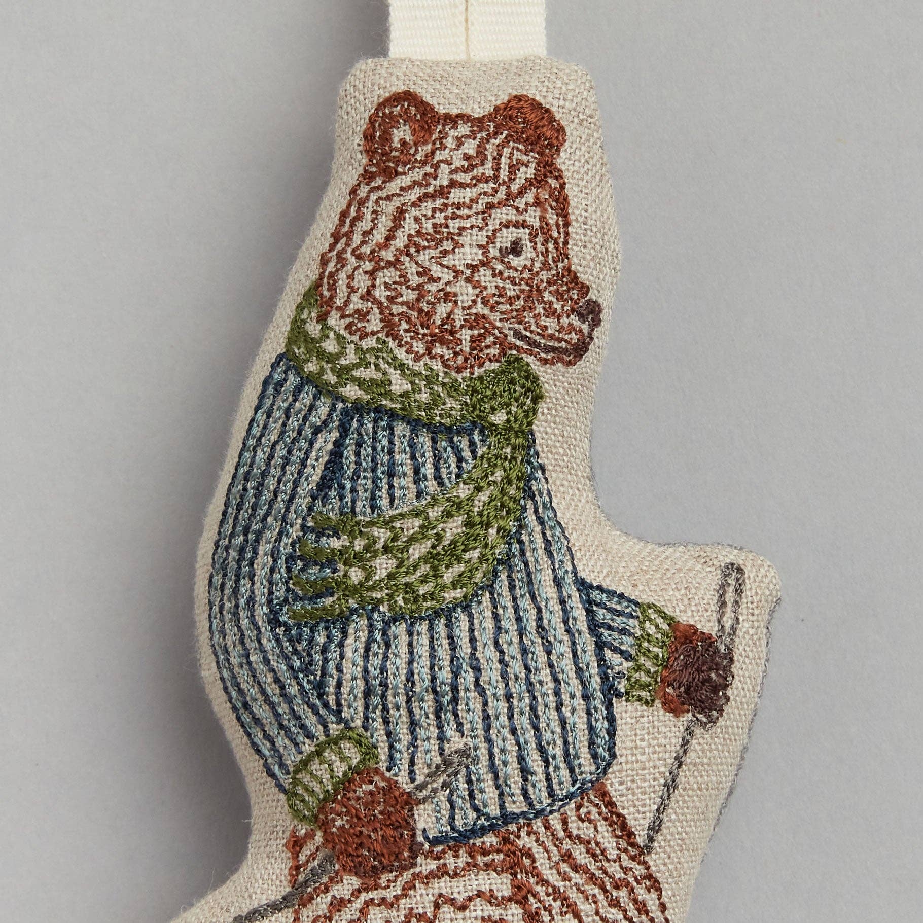 Textile bear ornament with a sweater and scarf on a gray background