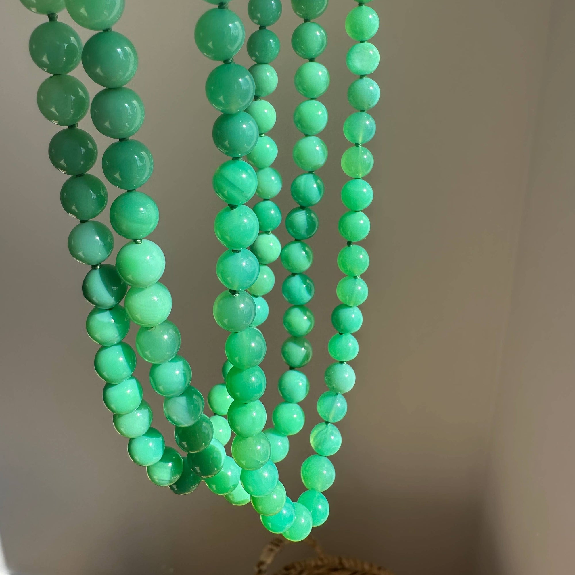 Green beaded necklace on a neutral background