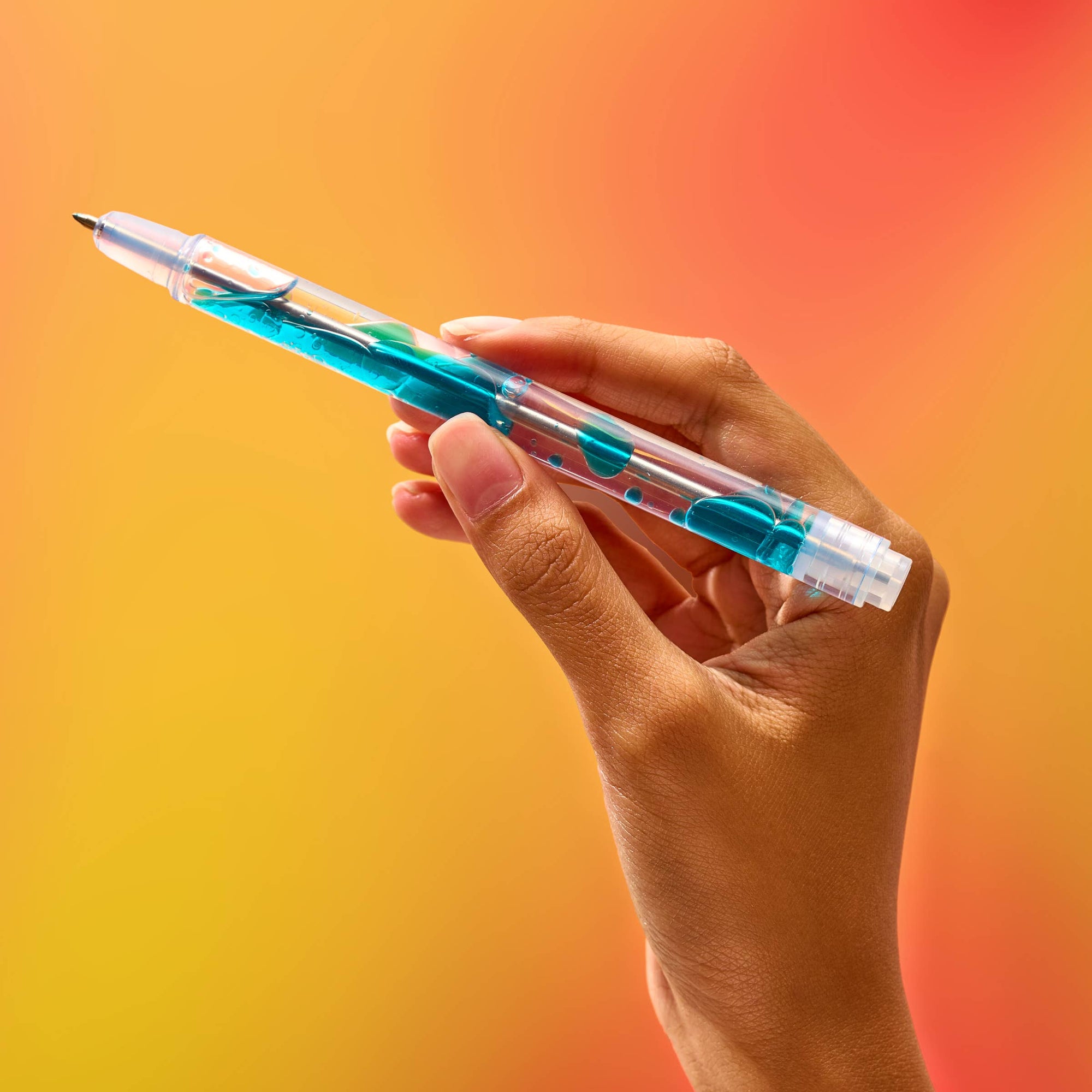 Hand holding a transparent pen with blue ink cartridge against a gradient background