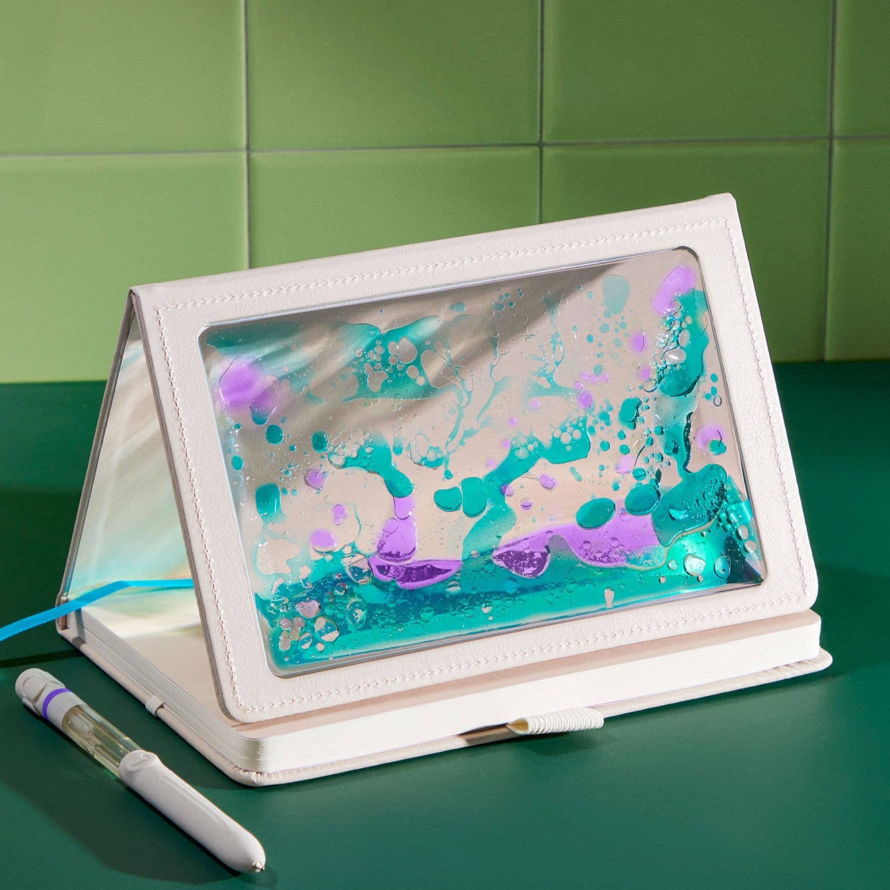 Tablet with a colorful screen and white case on a green surface with a green tiled wall background