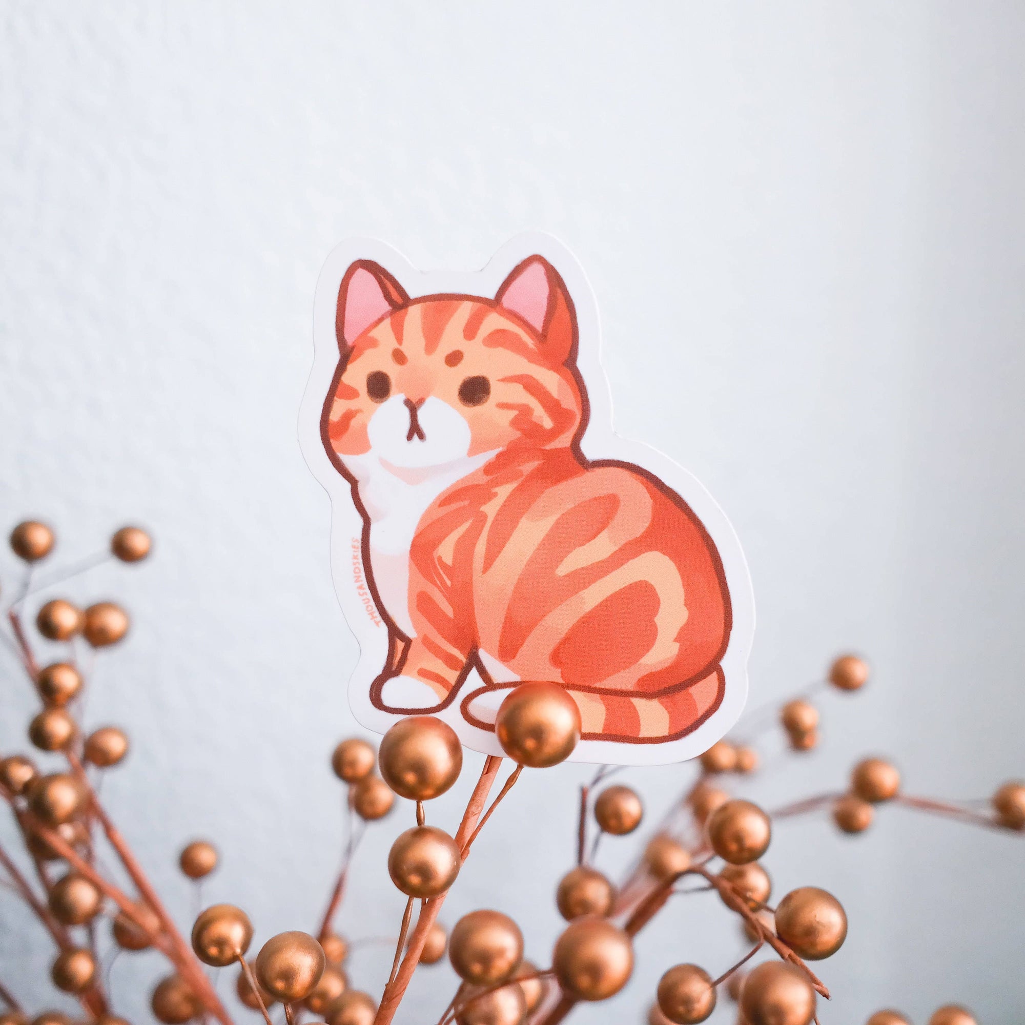 Cartoon cat sticker on a branch with small gold berries