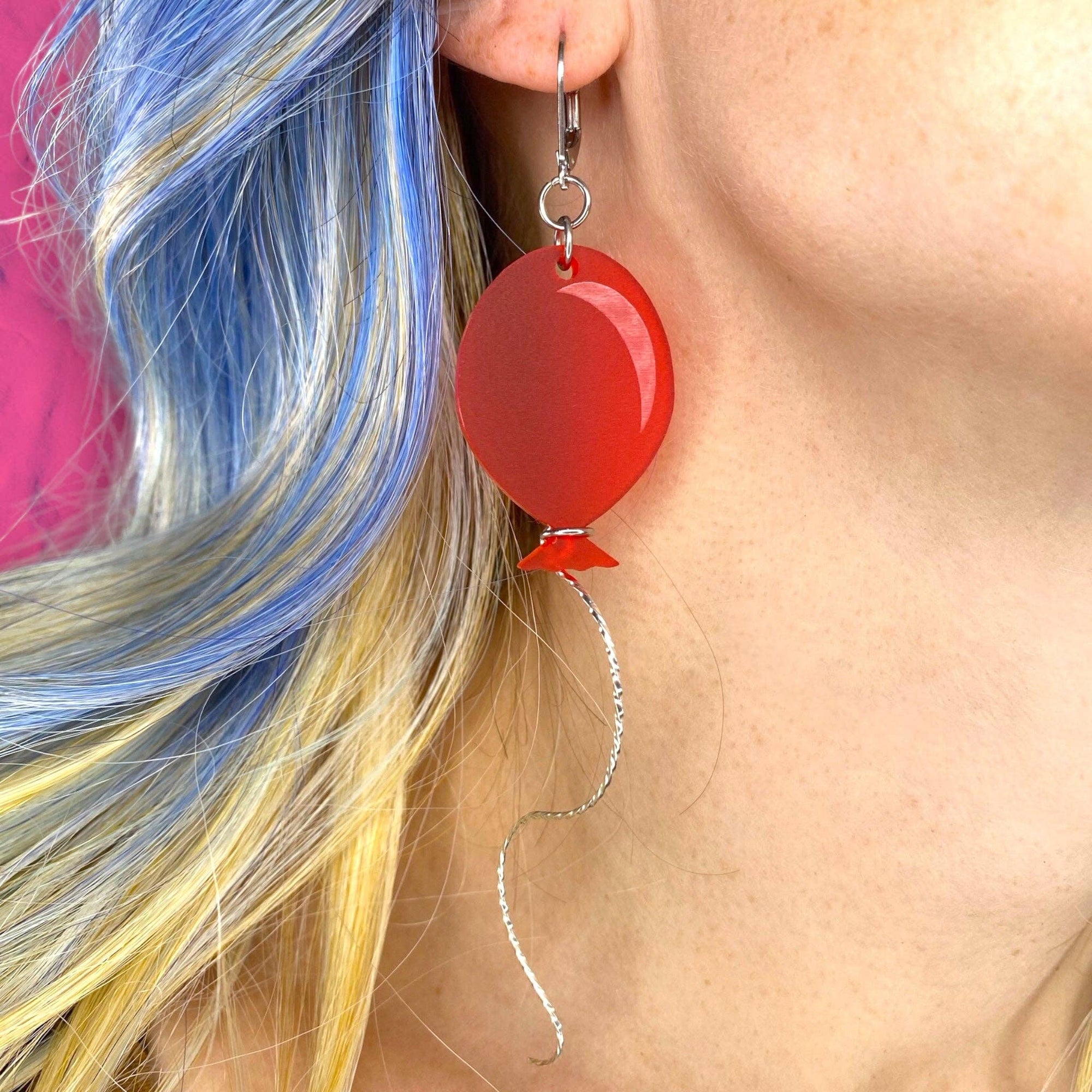 Red earrings worn by a person with colorful hair