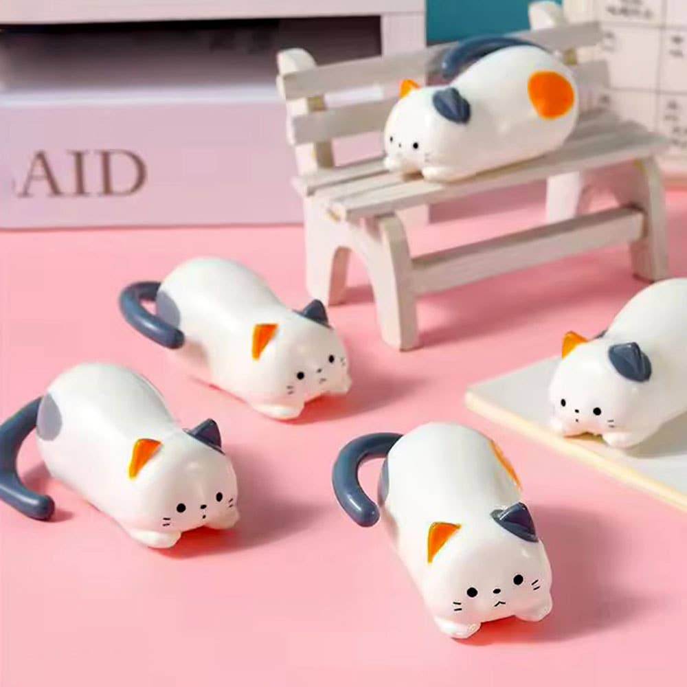 Cat-shaped desk organizers on a pink surface with a blurred background