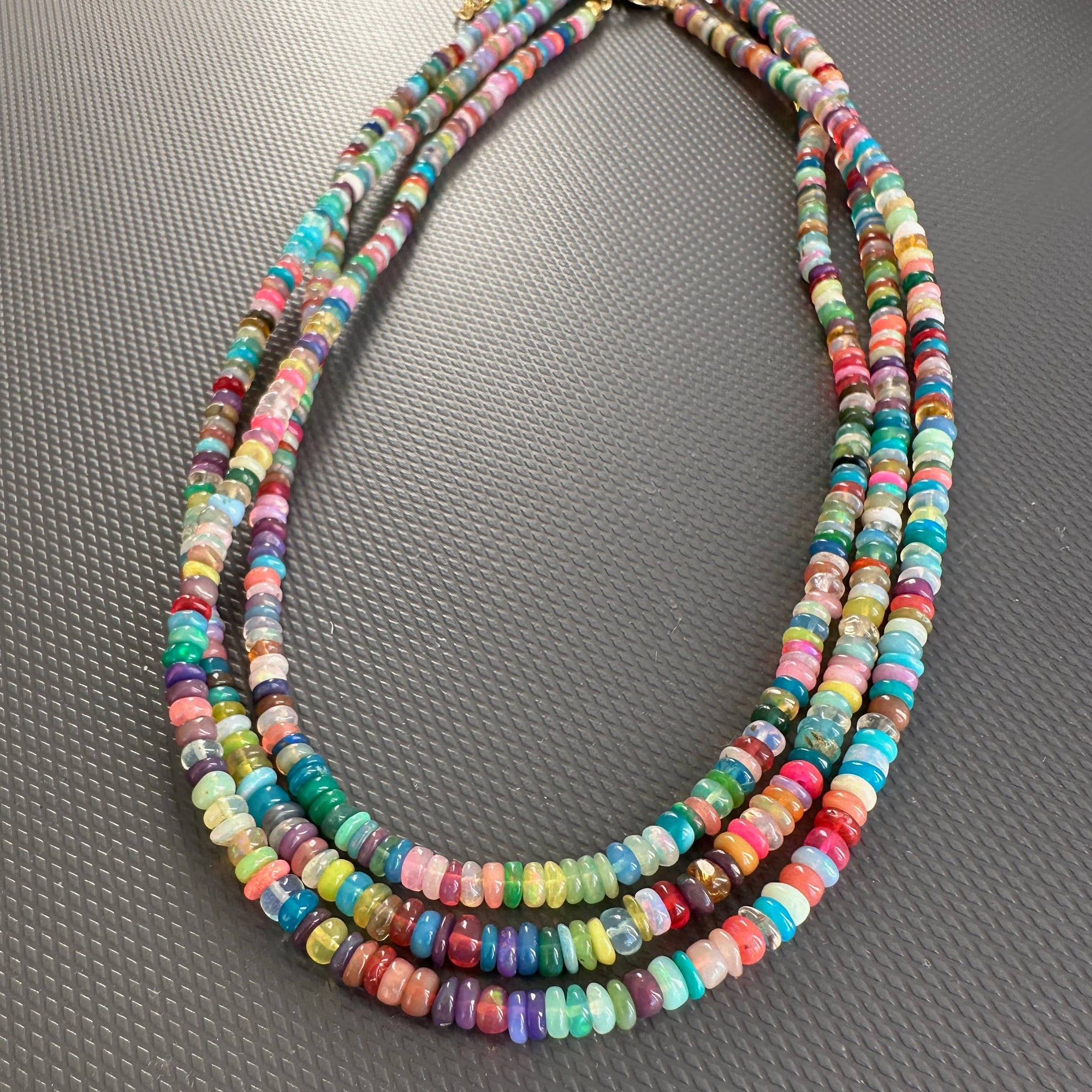 Multicolored beaded necklace on a gray textured surface