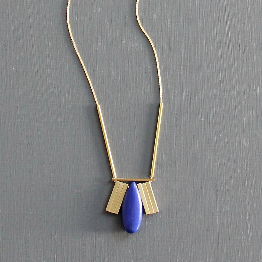 Gold necklace with a blue pendant on a gray background