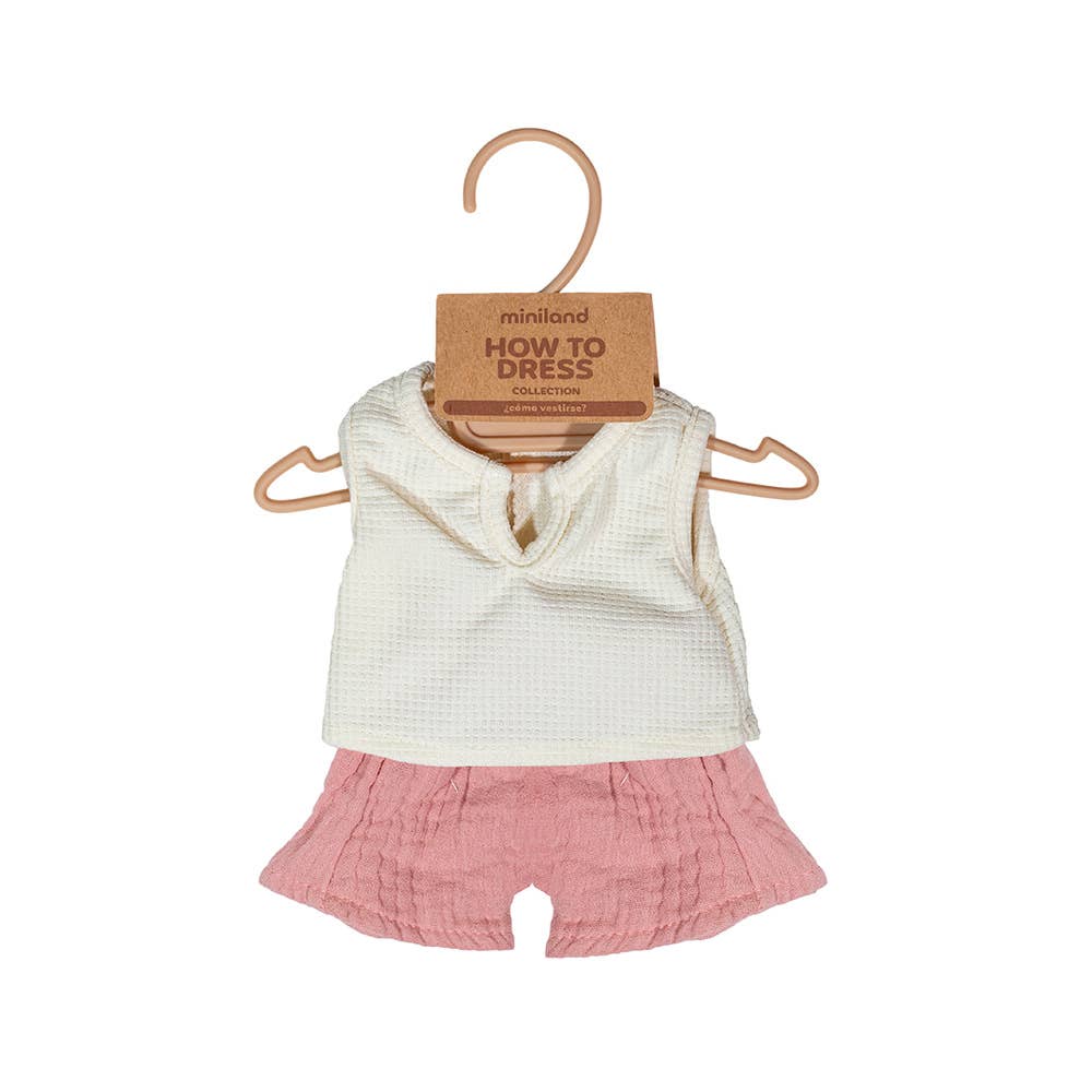 Baby outfit with white top and pink shorts on a hanger with 'miniland' label.