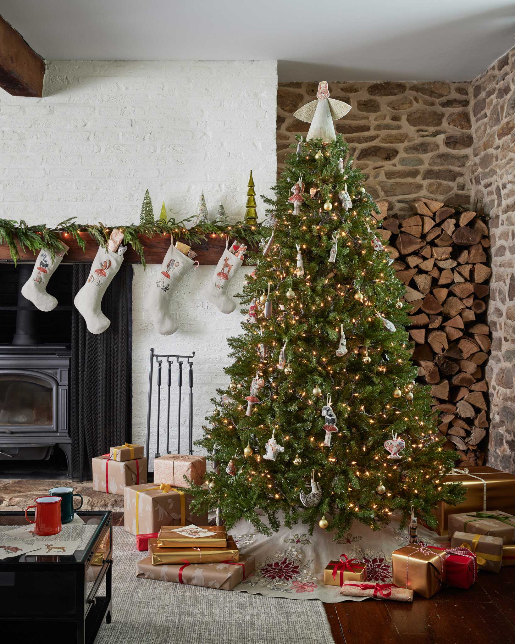 Decorated Christmas tree with lights in a living room with a fireplace and wooden mantel.