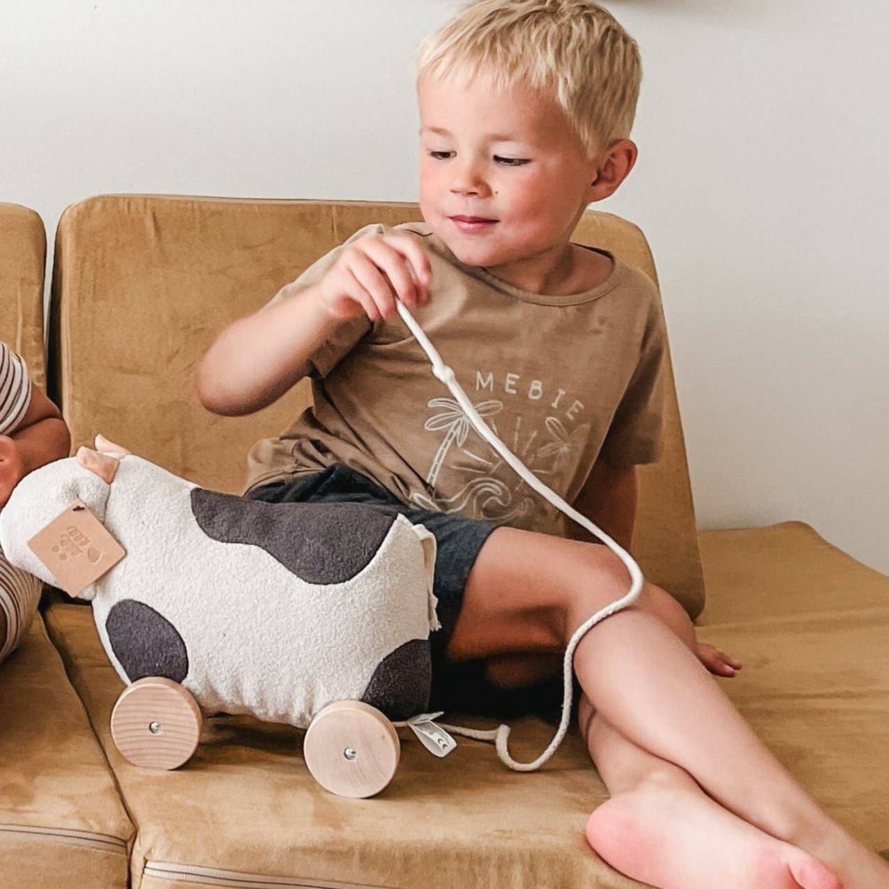 Child playing with a cow-shaped pull toy on a couch