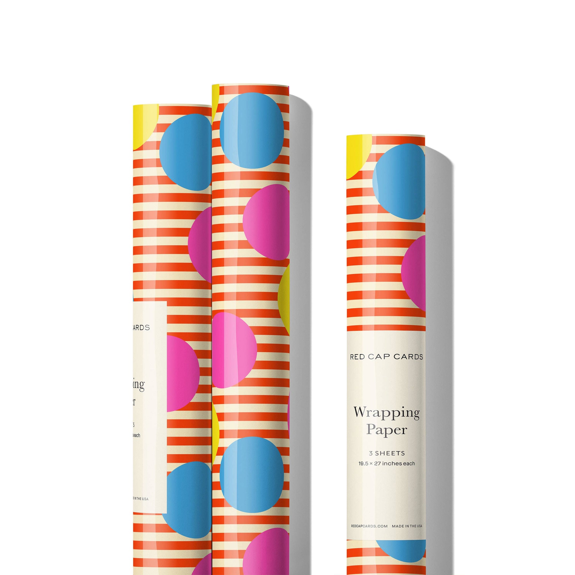 Three rolls of colorful wrapping paper with geometric patterns on a white background.
