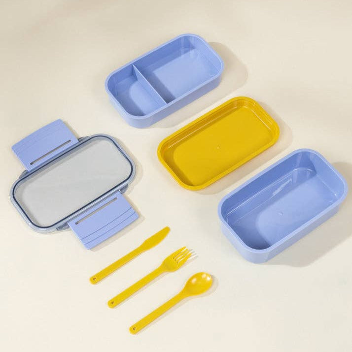 Set of colorful lunch boxes and utensils on a beige background