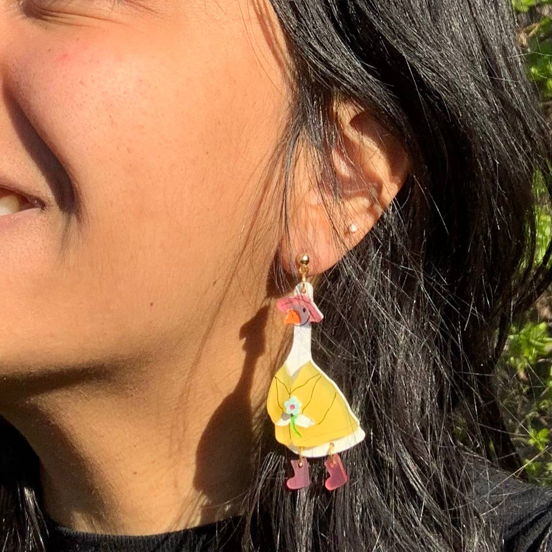 Close-up of a person wearing a unique earring with a yellow and pink design.