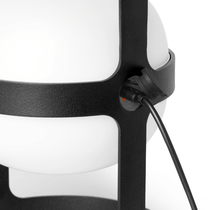 Close-up of a black and white light with a visible power cord.