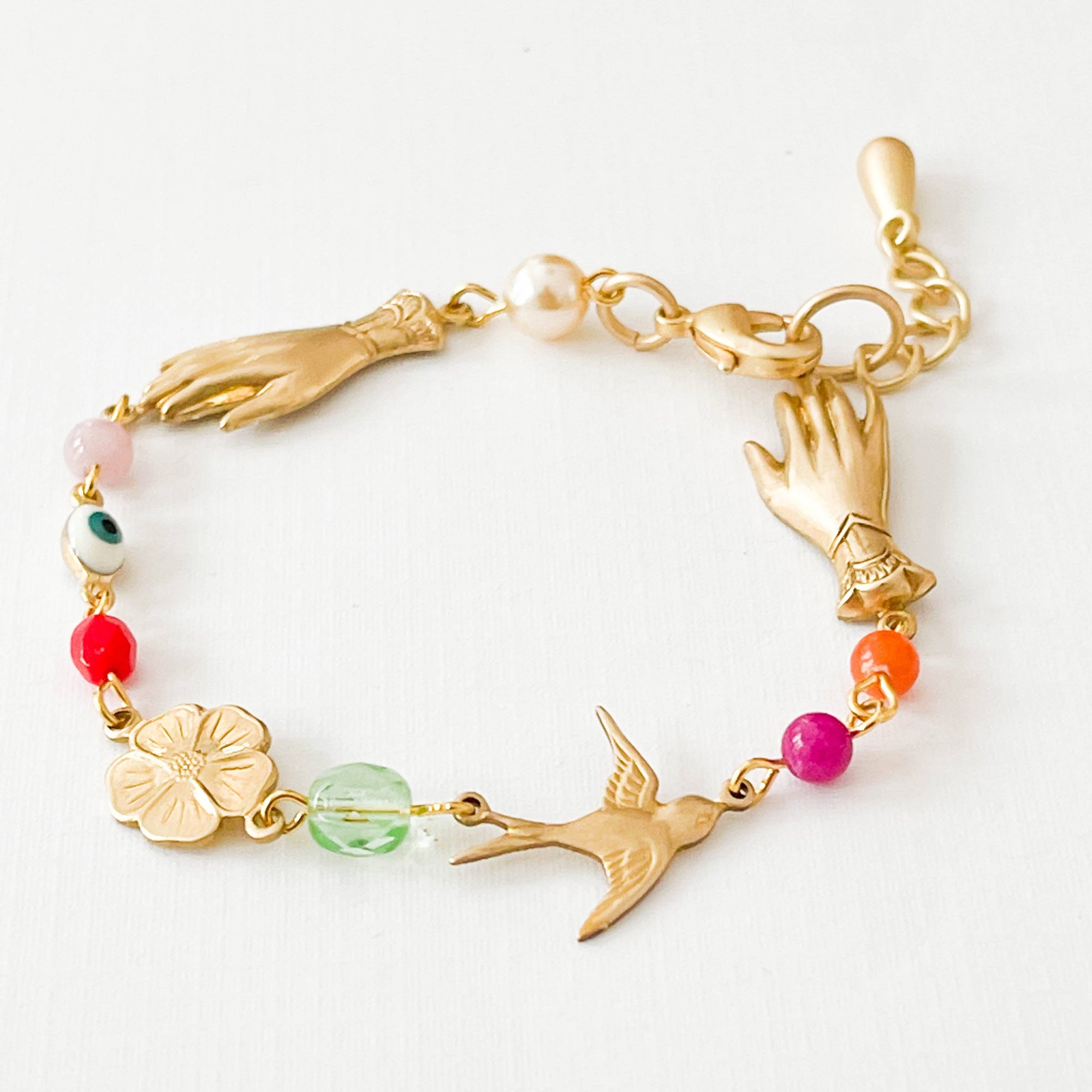 Gold bracelet with various charms on a white background
