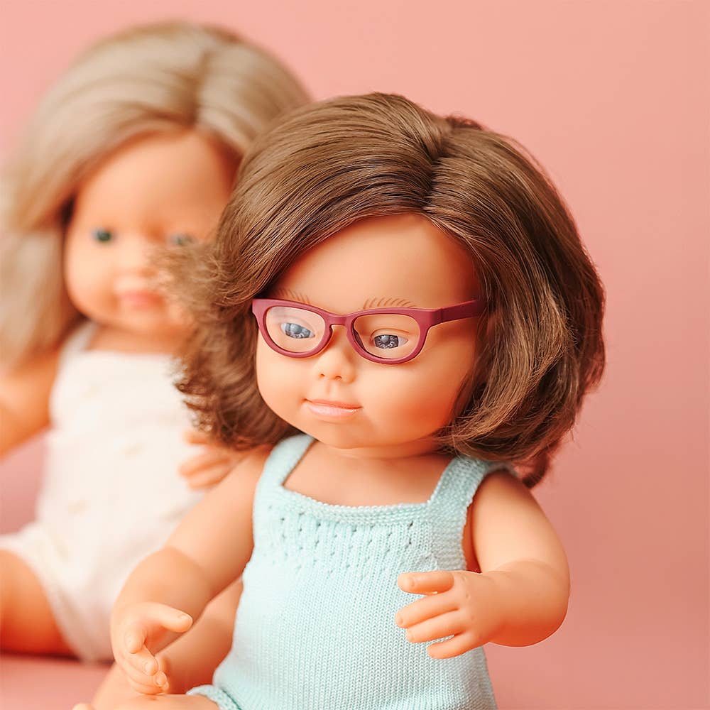 Two dolls with different hairstyles and outfits on a pink background