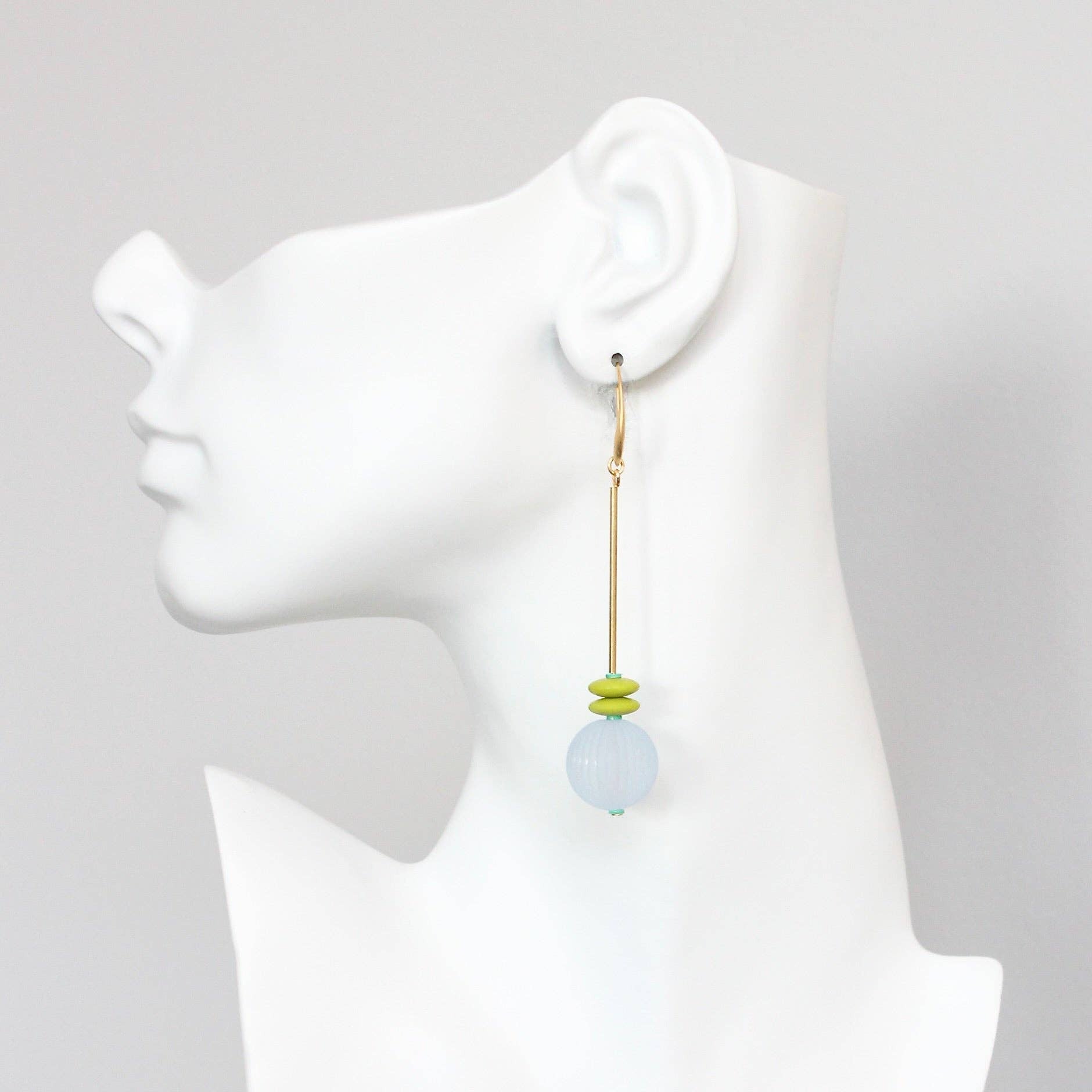 Earring on a mannequin ear with a plain background