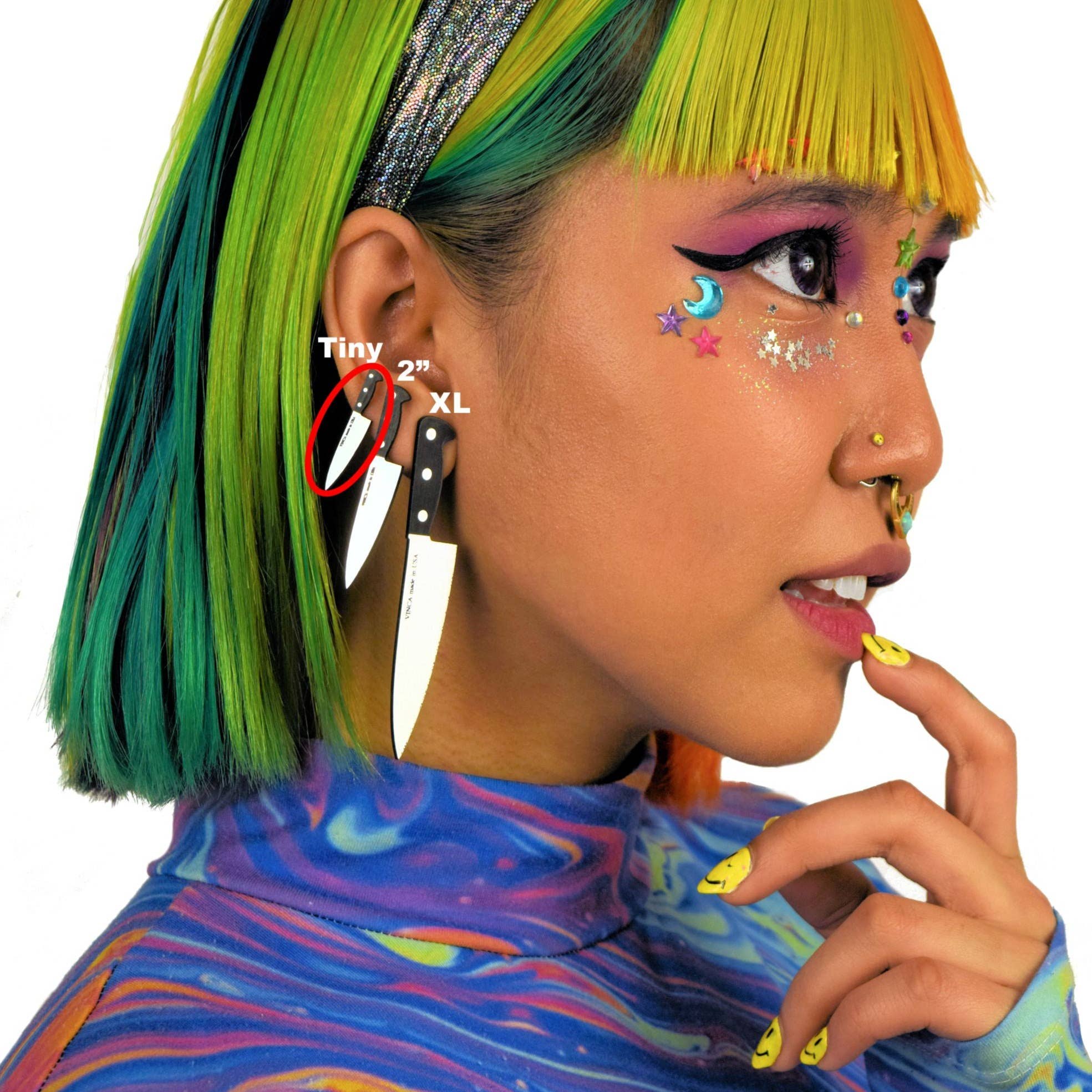 Person with colorful hair and makeup, wearing a blue and multicolor patterned top.