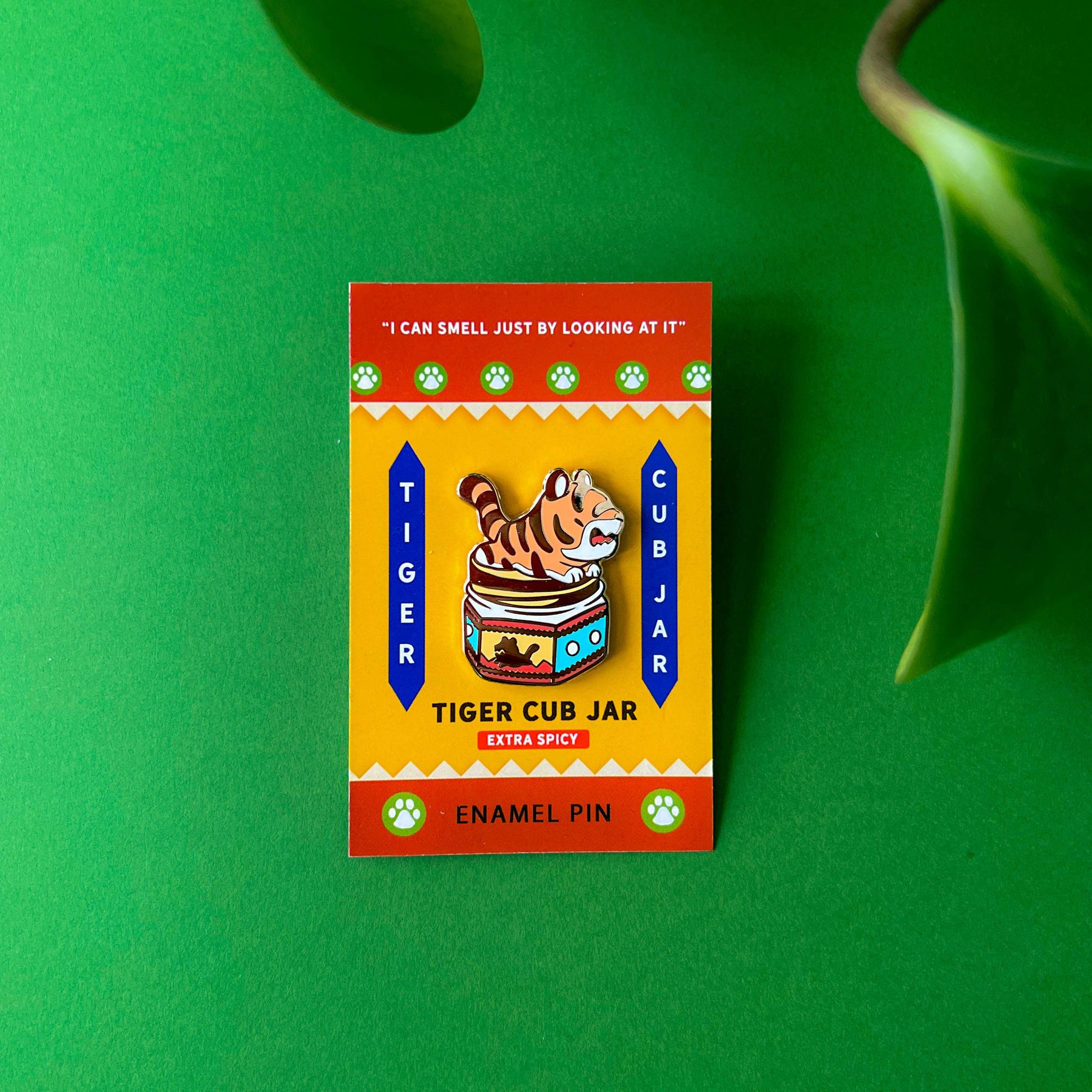 Enamel pin with tiger cub jar design on a green background