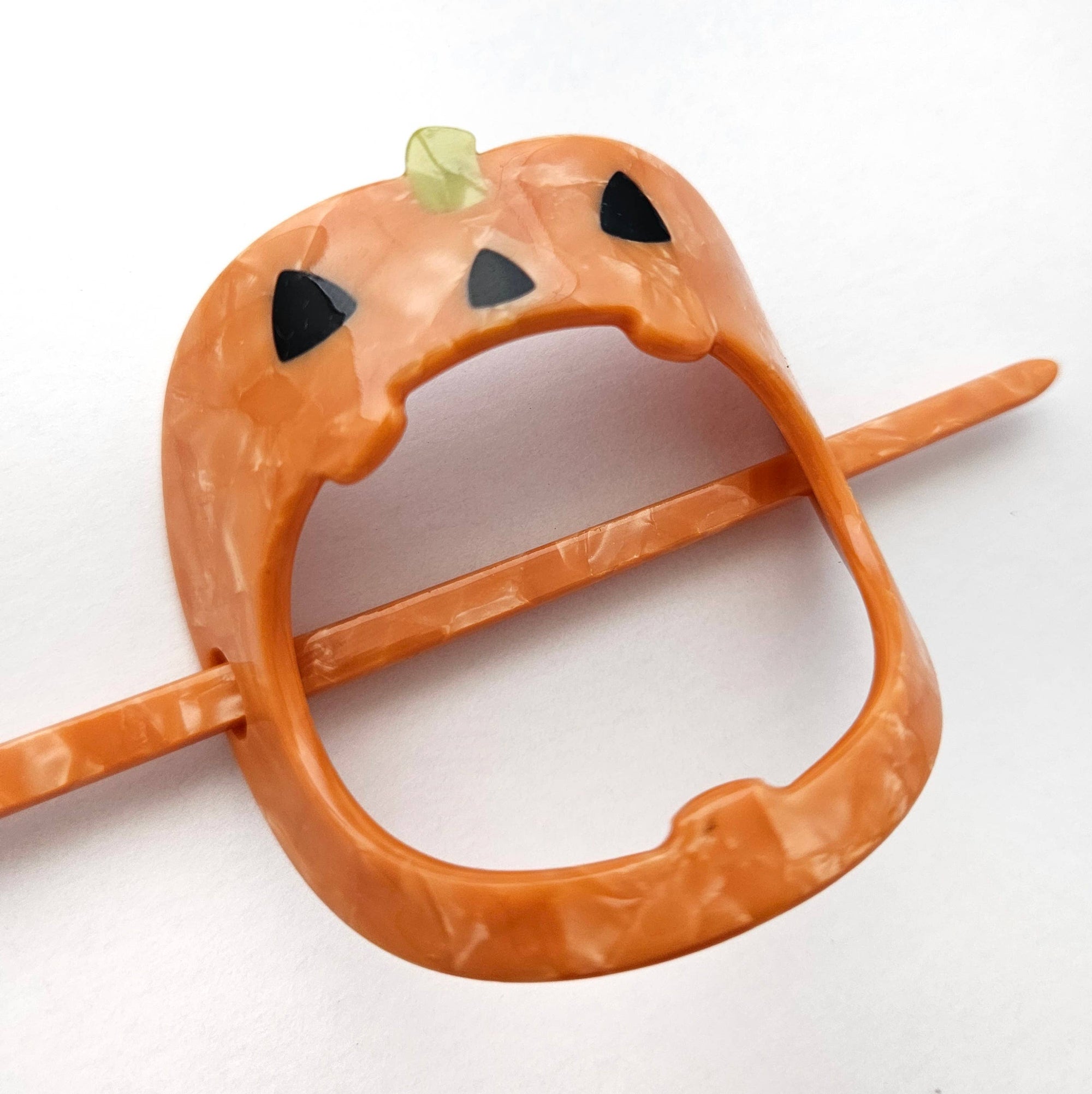 Orange snake-shaped toy with black eyes on a white background