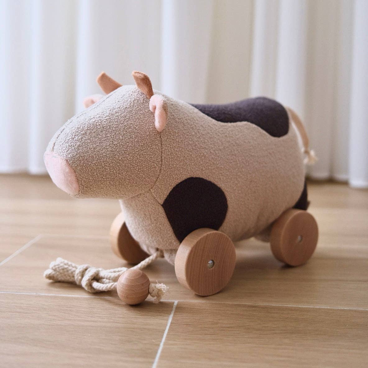 Children's toy cow with wheels on a wooden floor