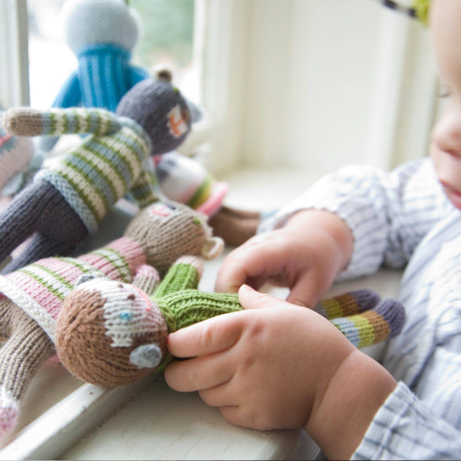 Child playing with knitted toys on a windowsill