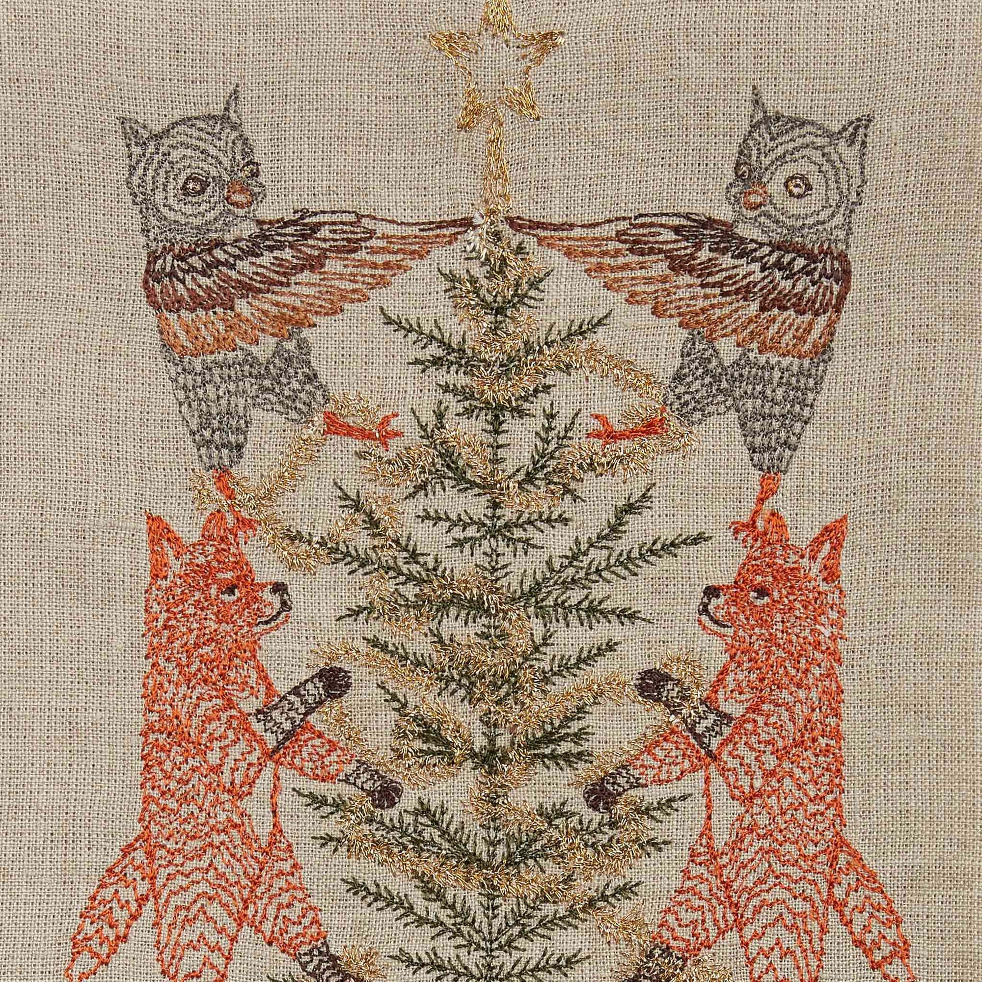 Embroidery of two foxes and two owls decorating a Christmas tree on a textured fabric background.