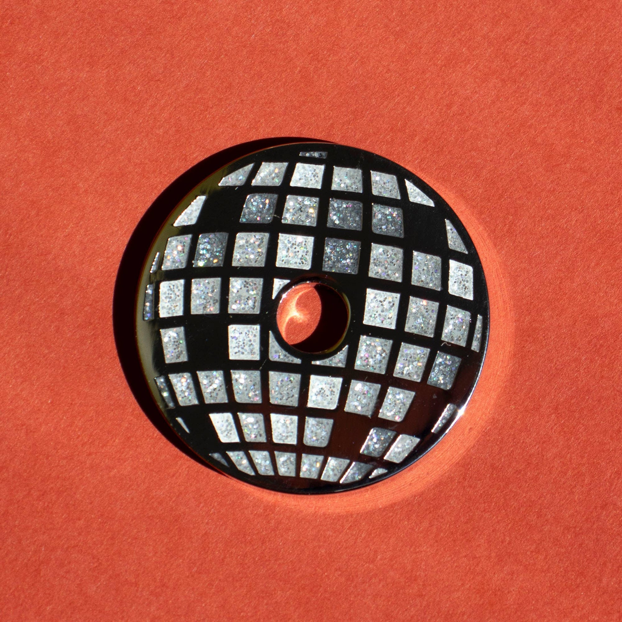 Round metallic object with grid pattern on a red background