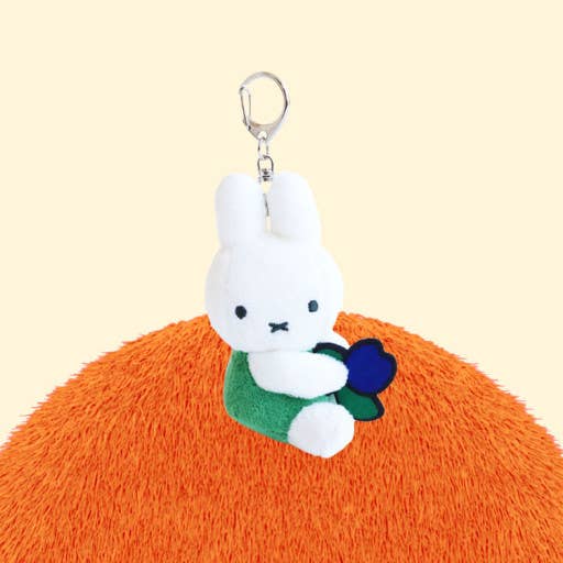 Plush keychain with a white character holding a blue flower on an orange background