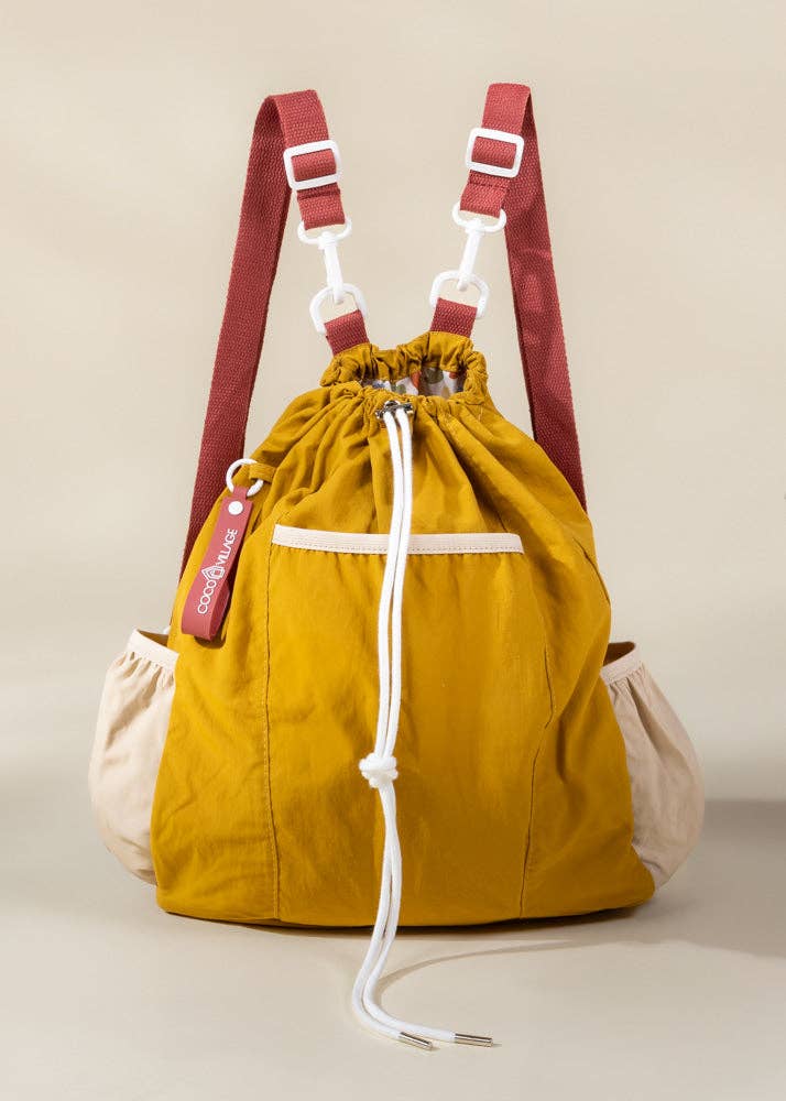 Yellow drawstring bag with red straps on a beige background