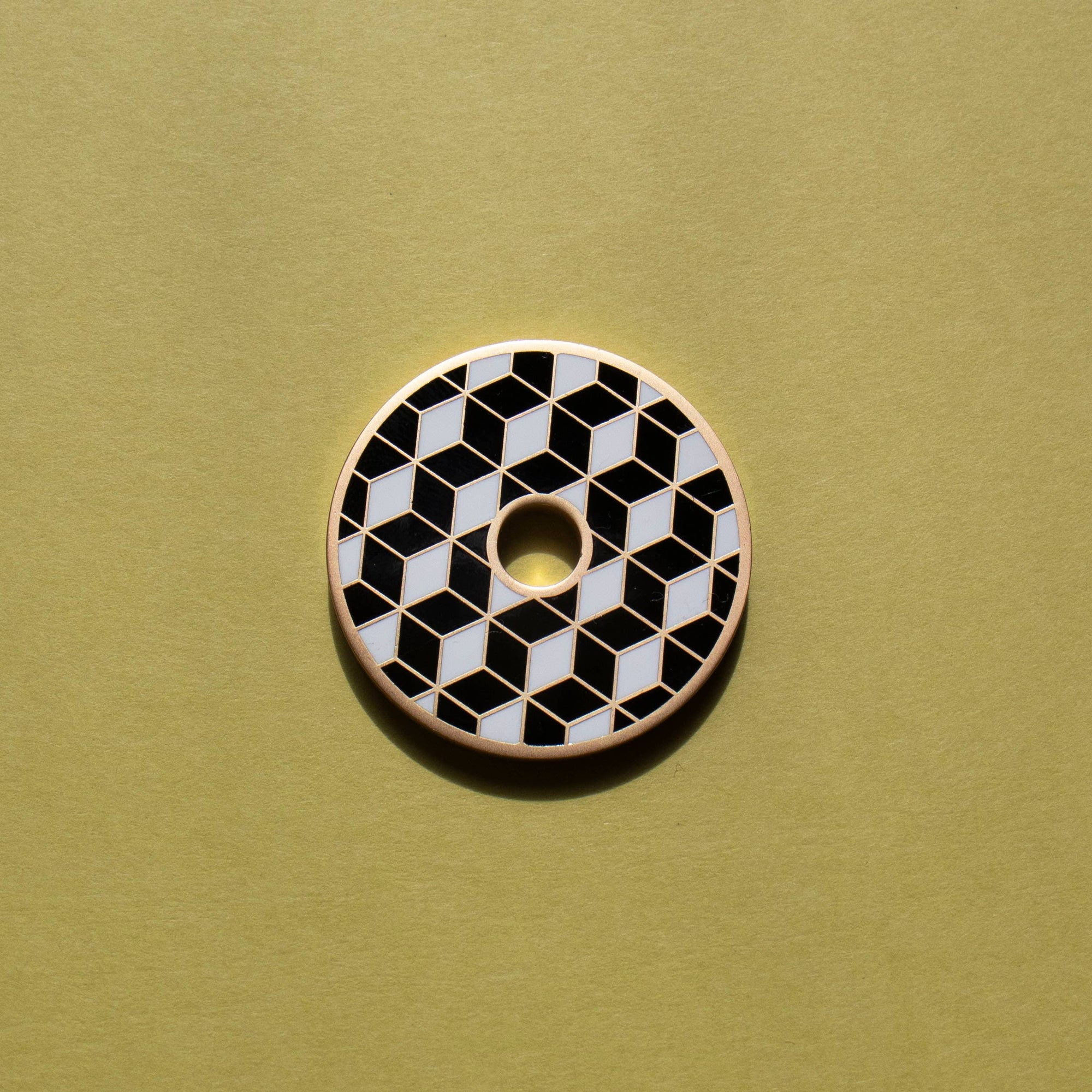 Circular button with black and white geometric pattern on a green background