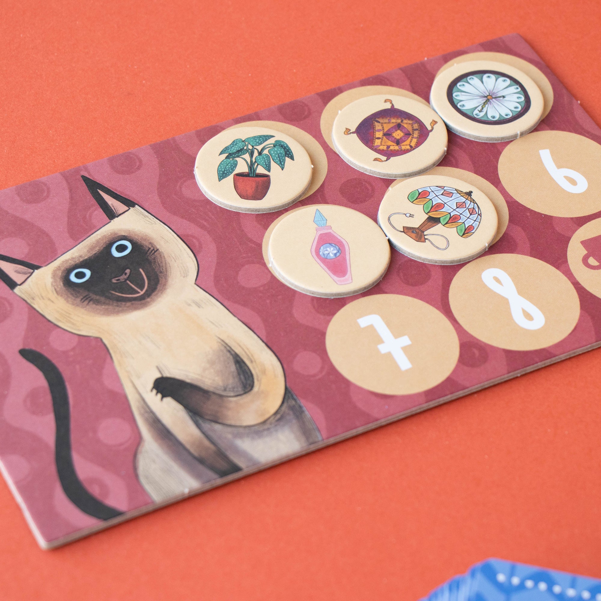 Board game piece with a cat illustration and numbered and symbolized circles on a red background