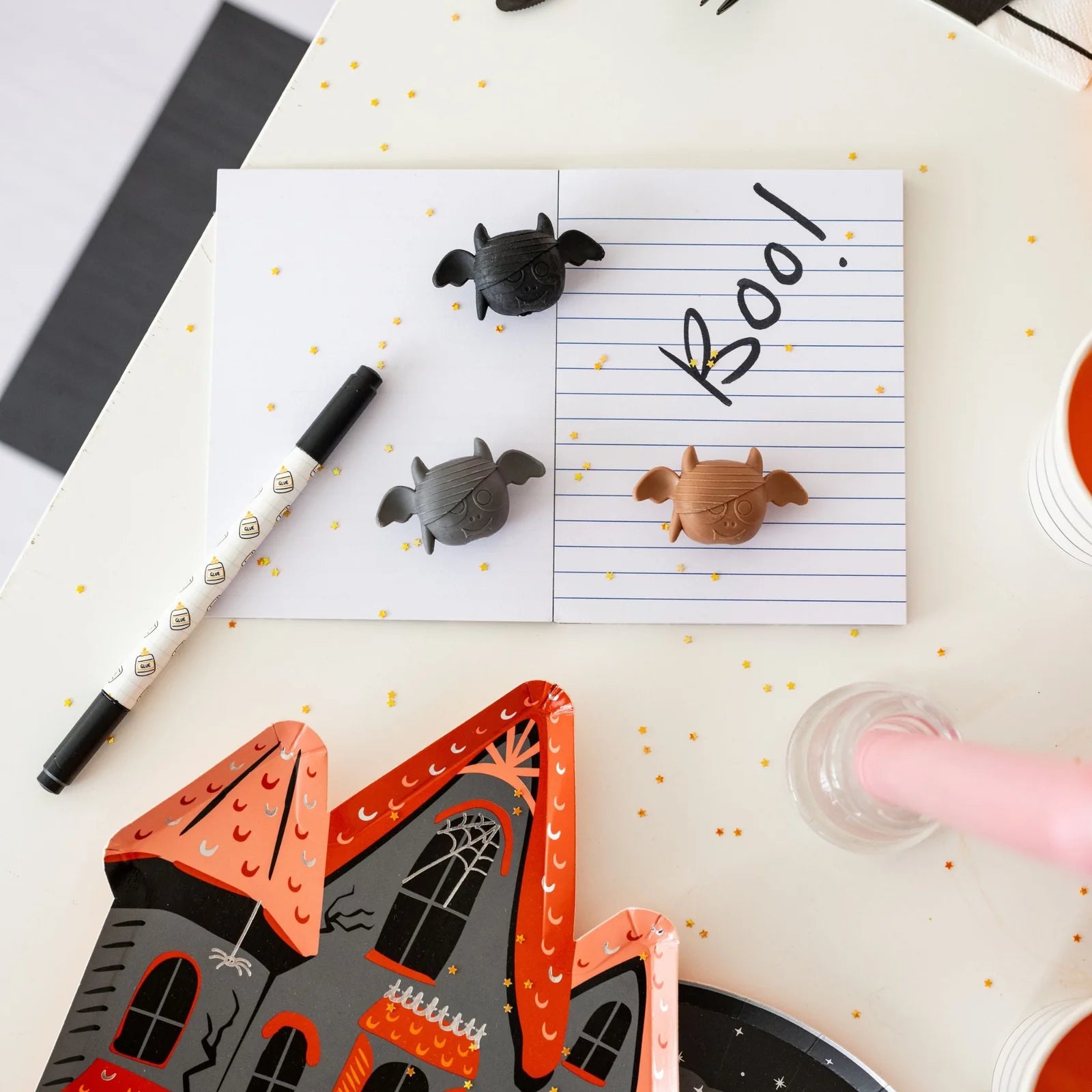 Halloween-themed stationery items including a haunted house card, pen, and small animal figurines on a polka dot surface.