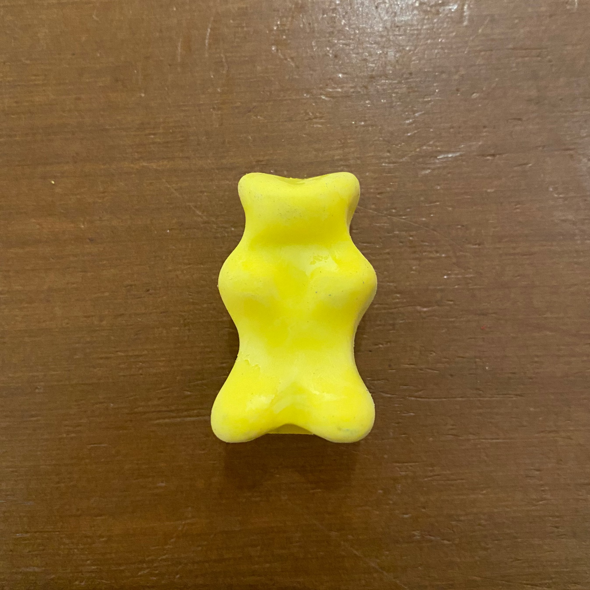 Yellow bear-shaped object on a wooden surface