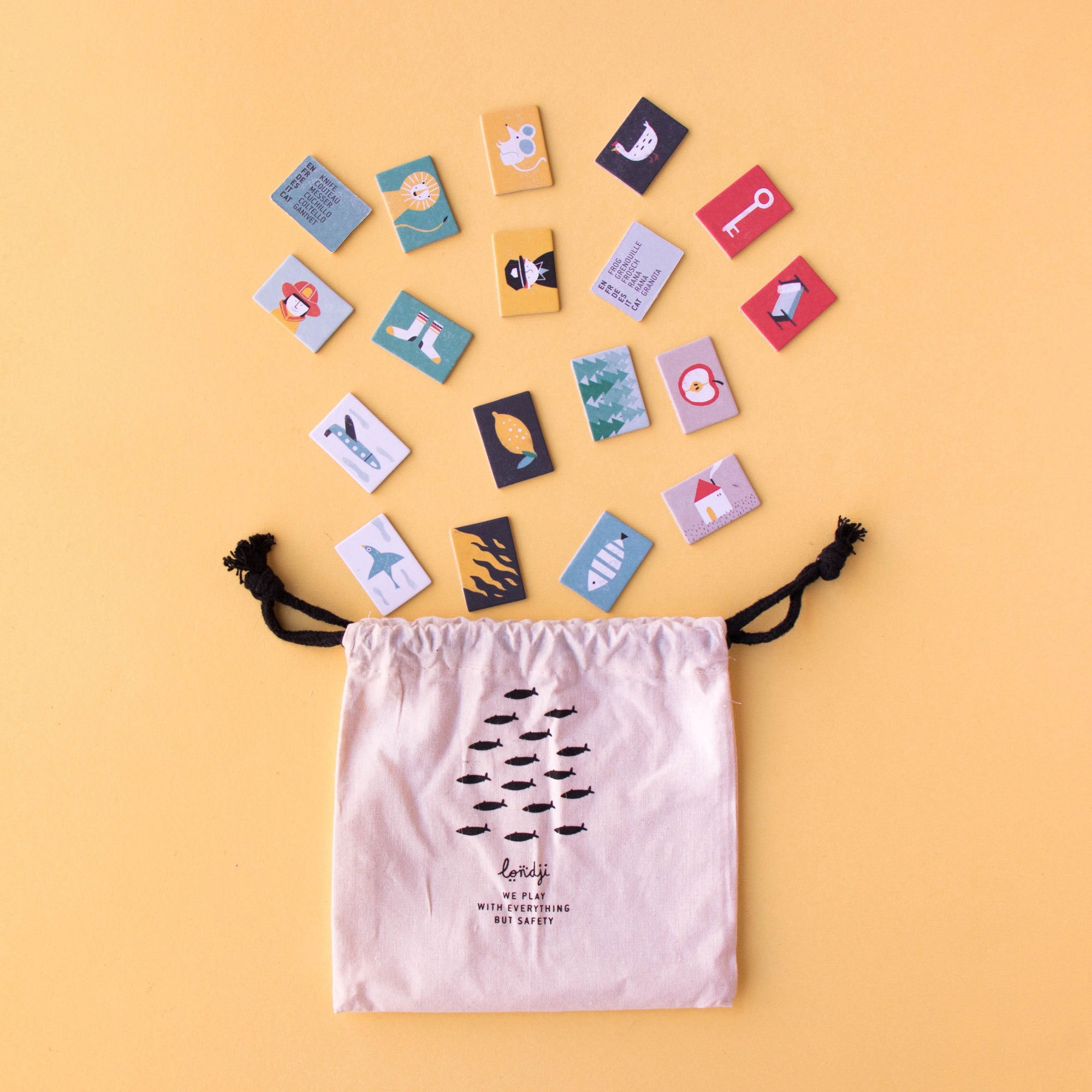 Colorful game cards arranged around a drawstring bag on a yellow background