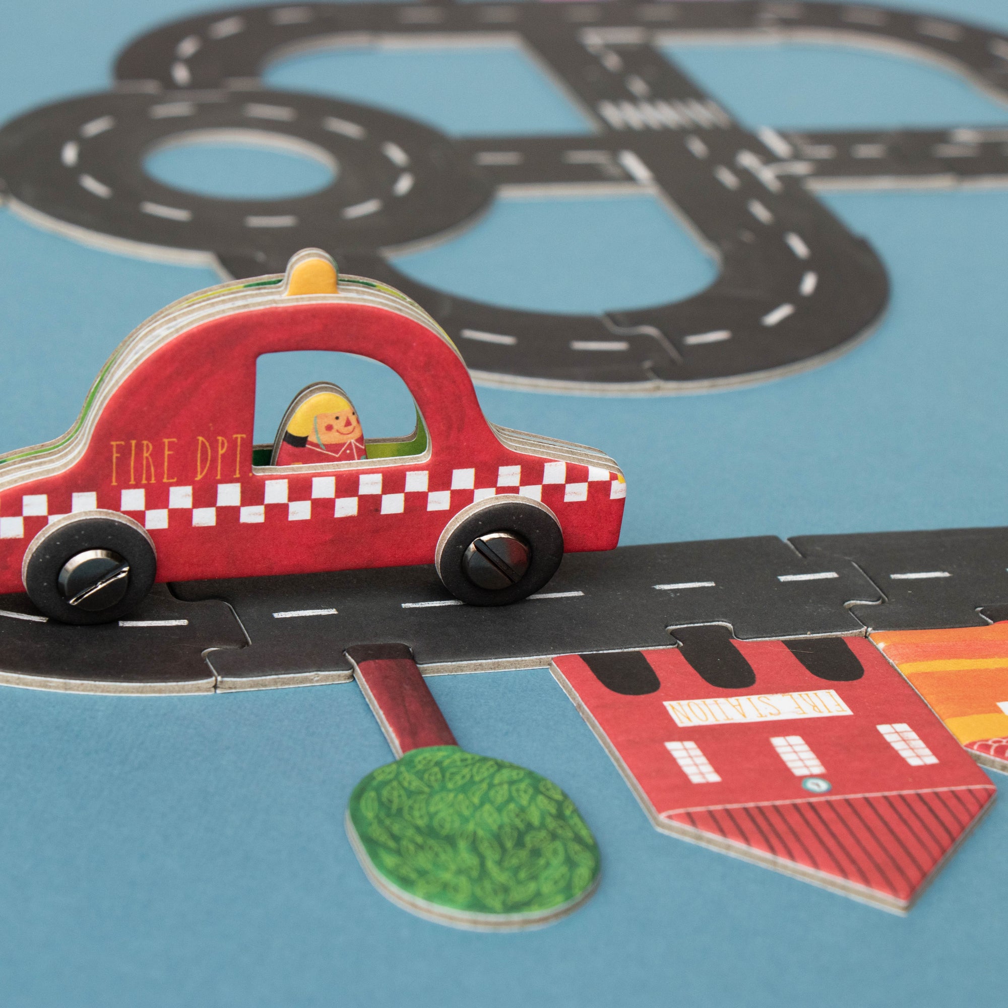 Toy fire truck on a road track with a blue background