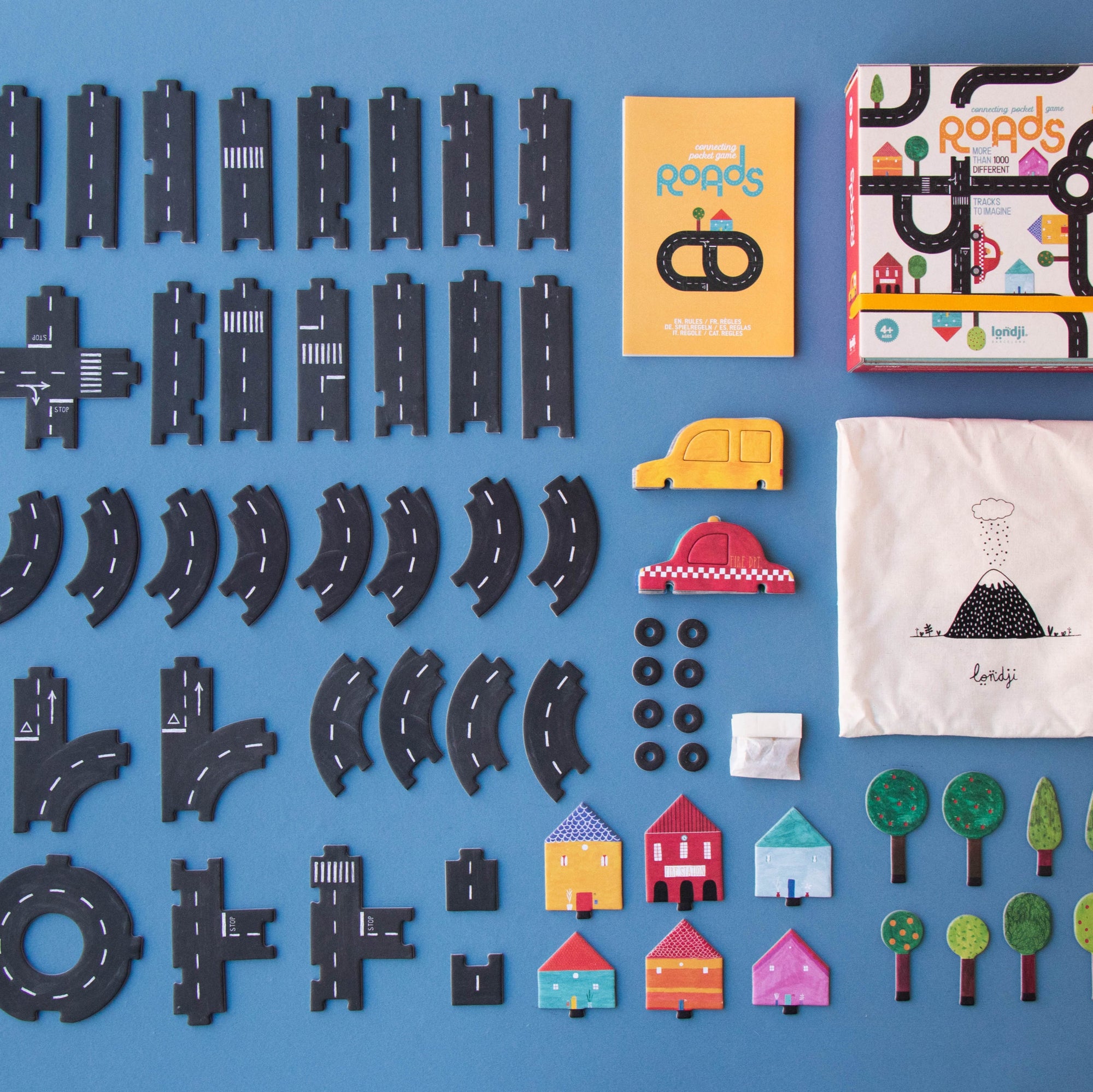 Collection of toy road pieces, building blocks, and small items on a blue background