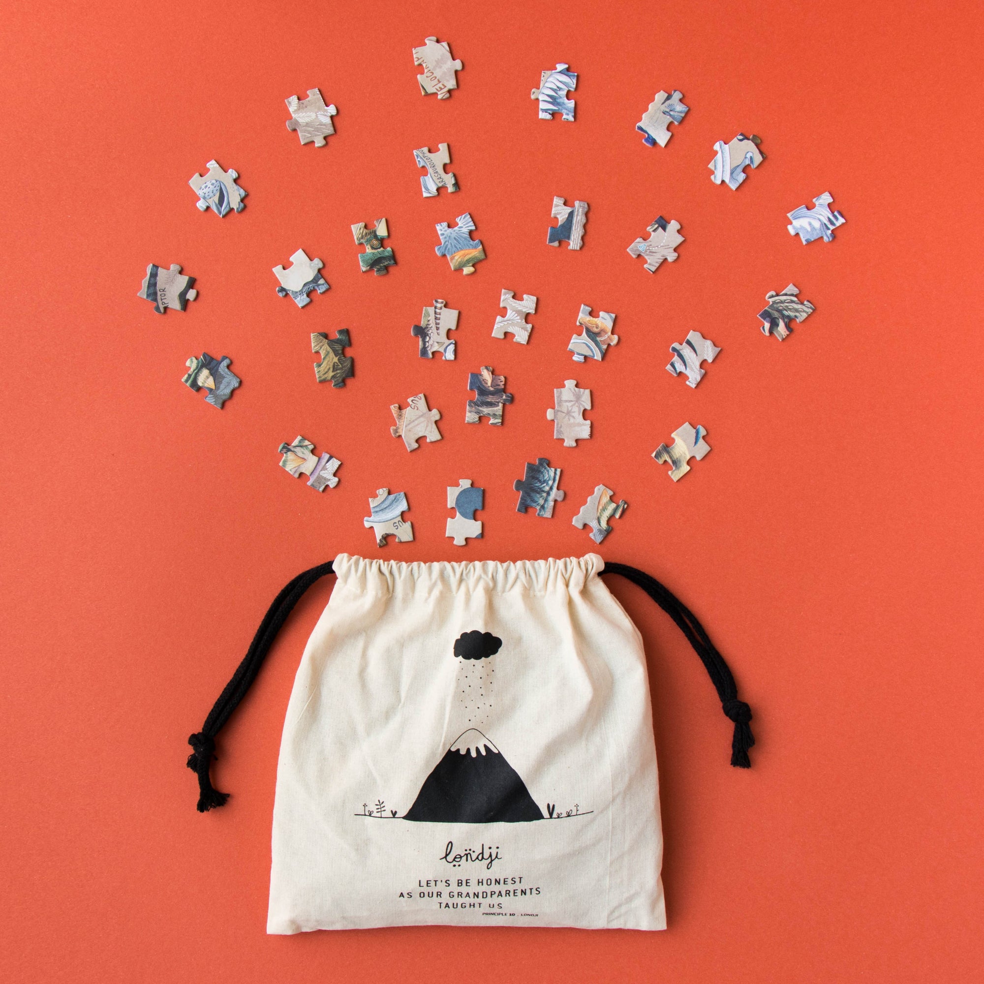Drawstring bag with puzzle pieces spilling out on an orange background