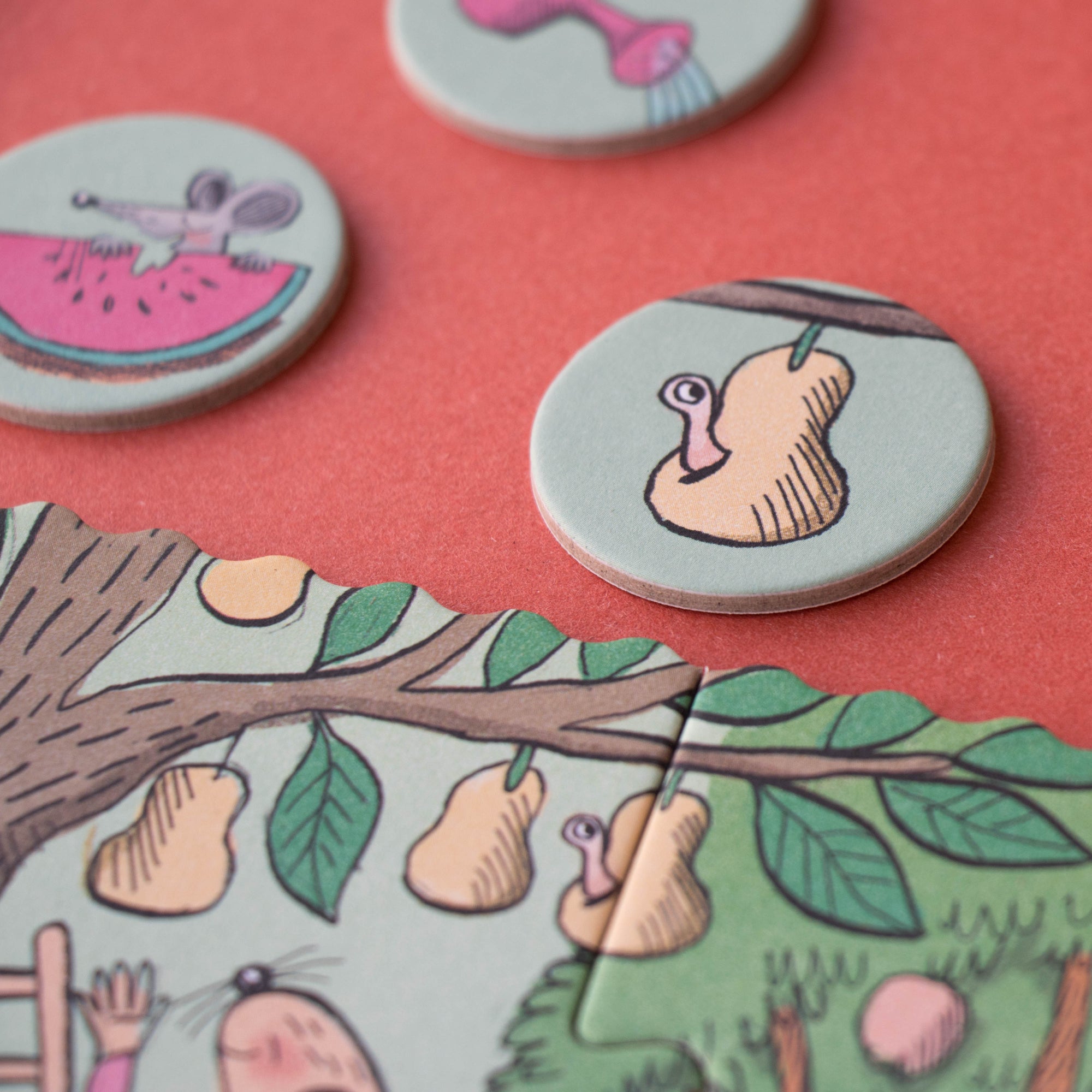 Round game pieces with cartoonish illustrations on a pink background