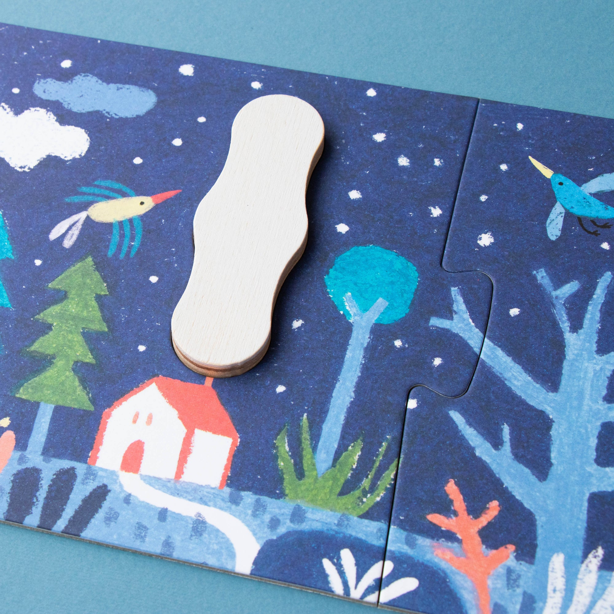 Children's puzzle with a blue background featuring trees, houses, and birds.