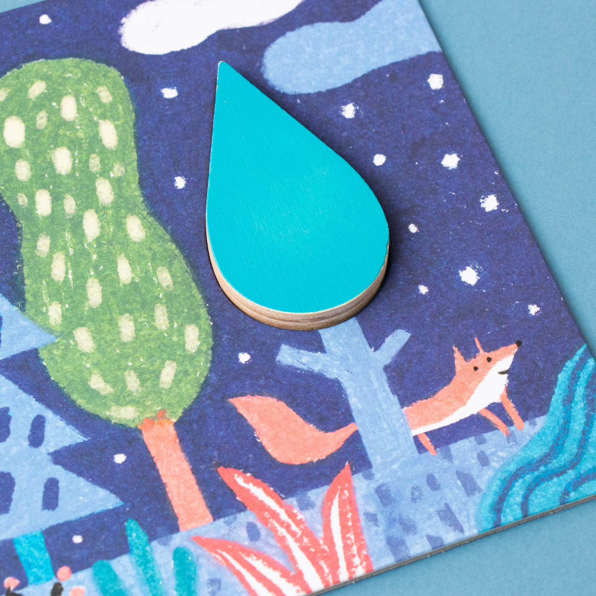 Children's illustration of a forest scene with a tree, fox, and raindrop on a blue background.