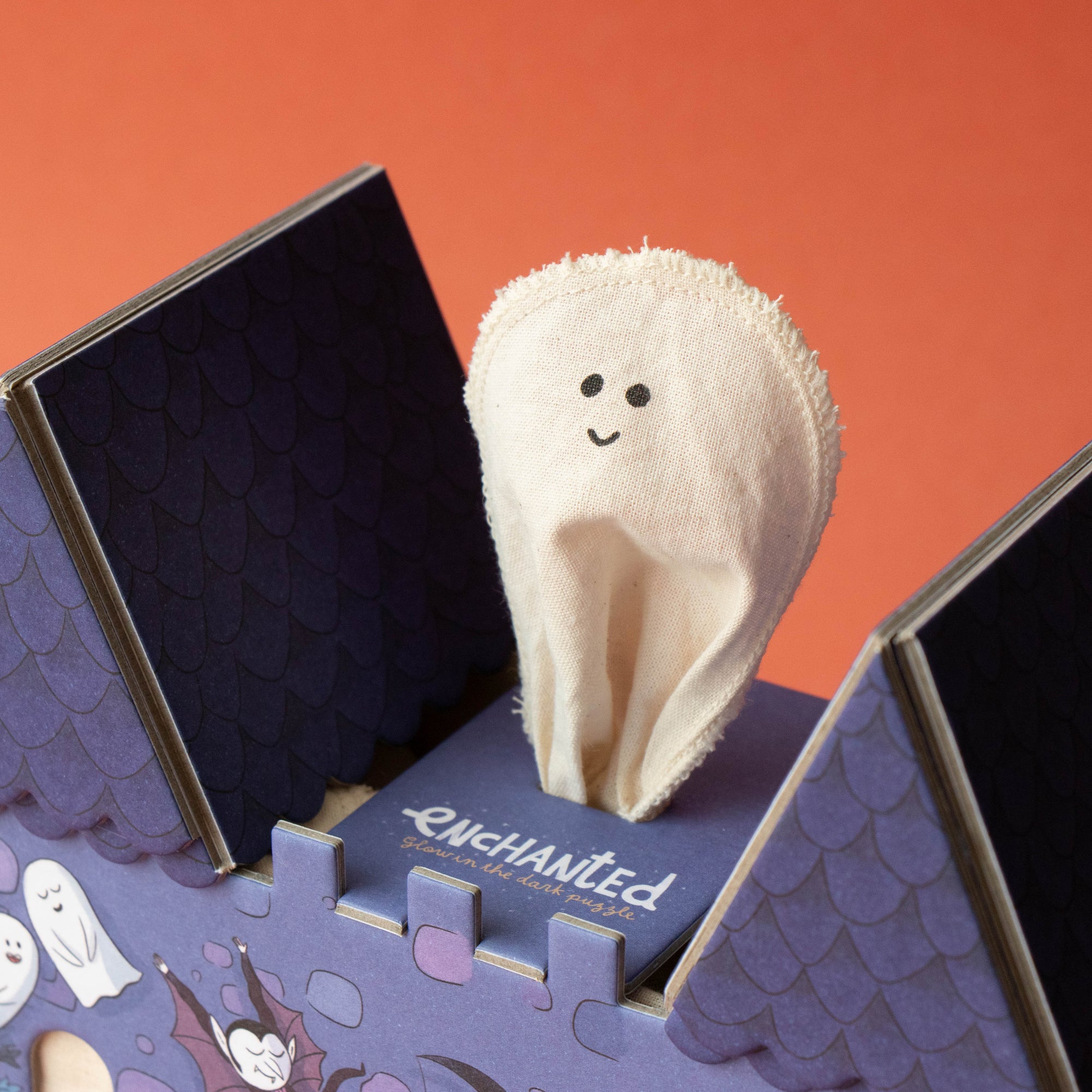 Small plush ghost toy inside a Halloween-themed box with a red background